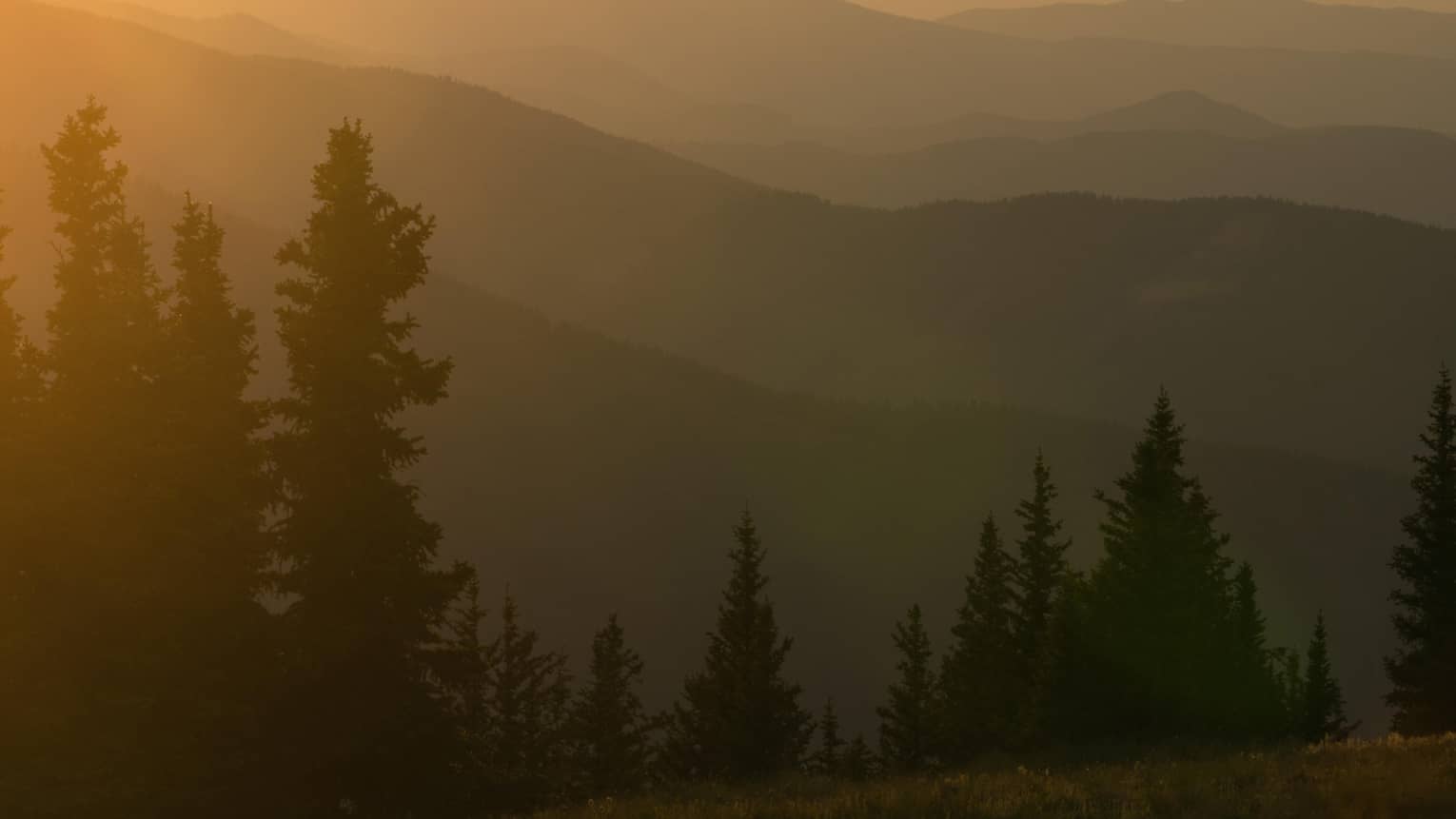 Helicopter at sunset flying over Aspen Mountain in the Elks Mountain range