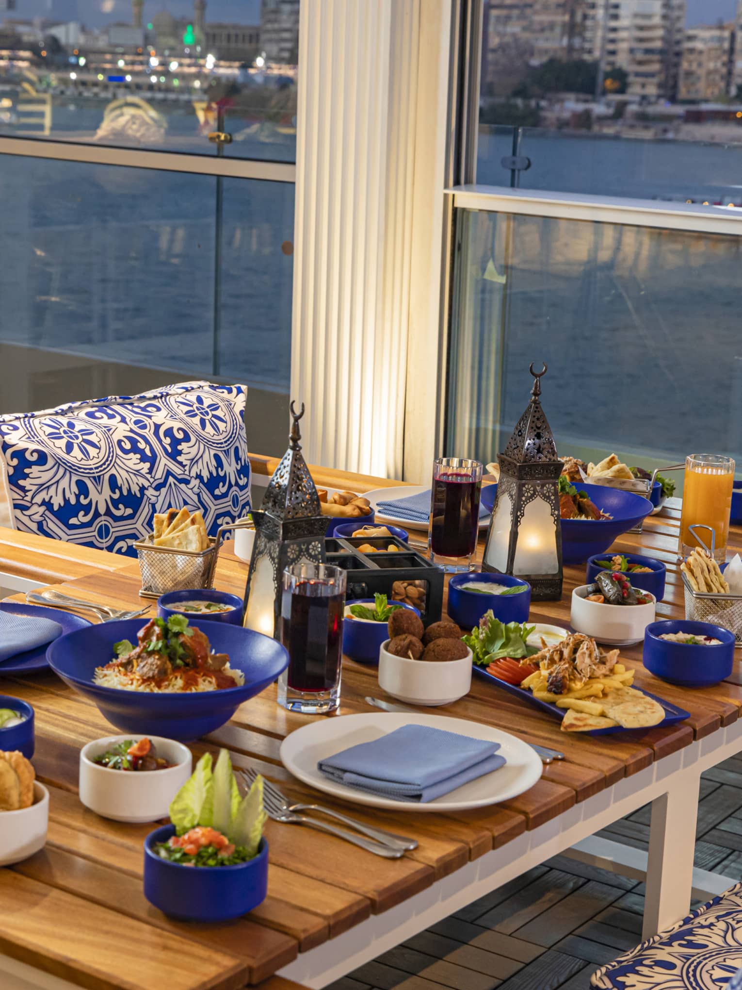 Dishes for Ramadan on wooden table for four at Zo�, the Nile and cityscape visible in background