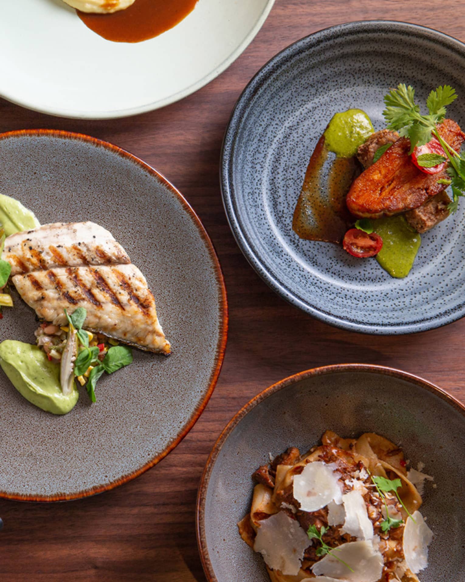 Aerial view of dinner plates on table with large grilled chicken breast, steak 