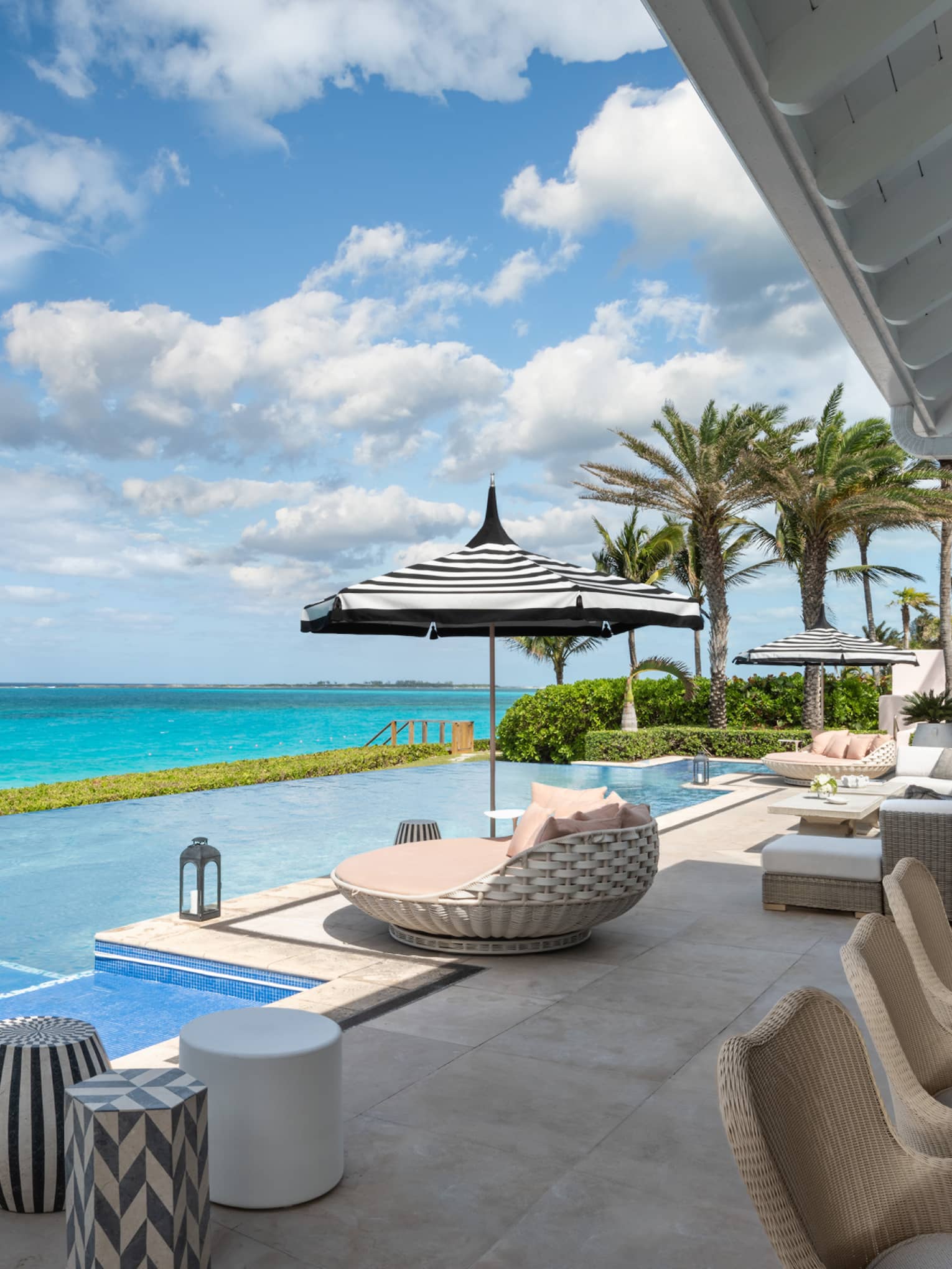 Beachfront villa residence terrace with private infinity pool, sun loungers, and ocean view under a bright blue sky