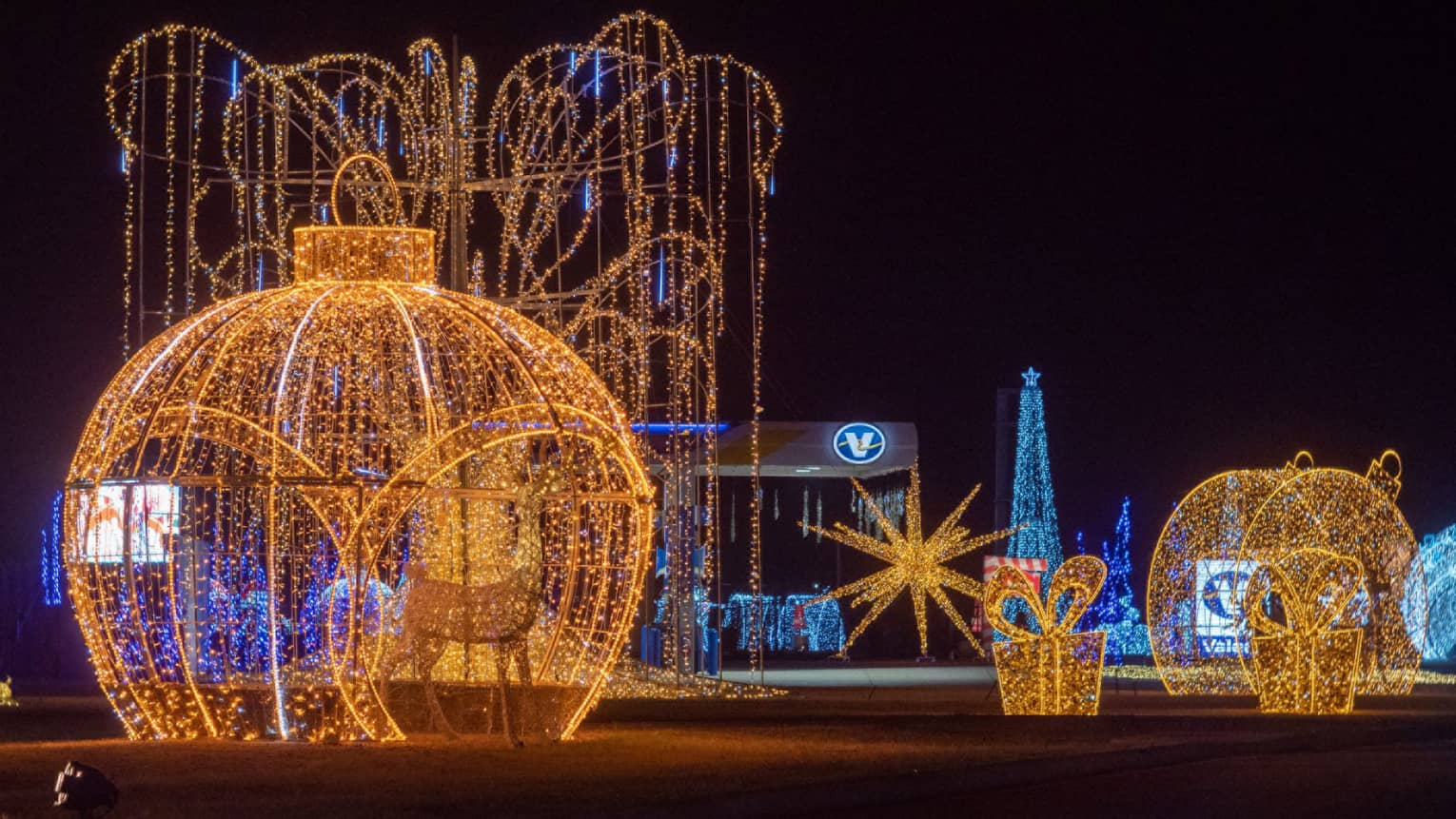 Large sculptures made out of metal and glowing Christmas lights including ornaments and presents.