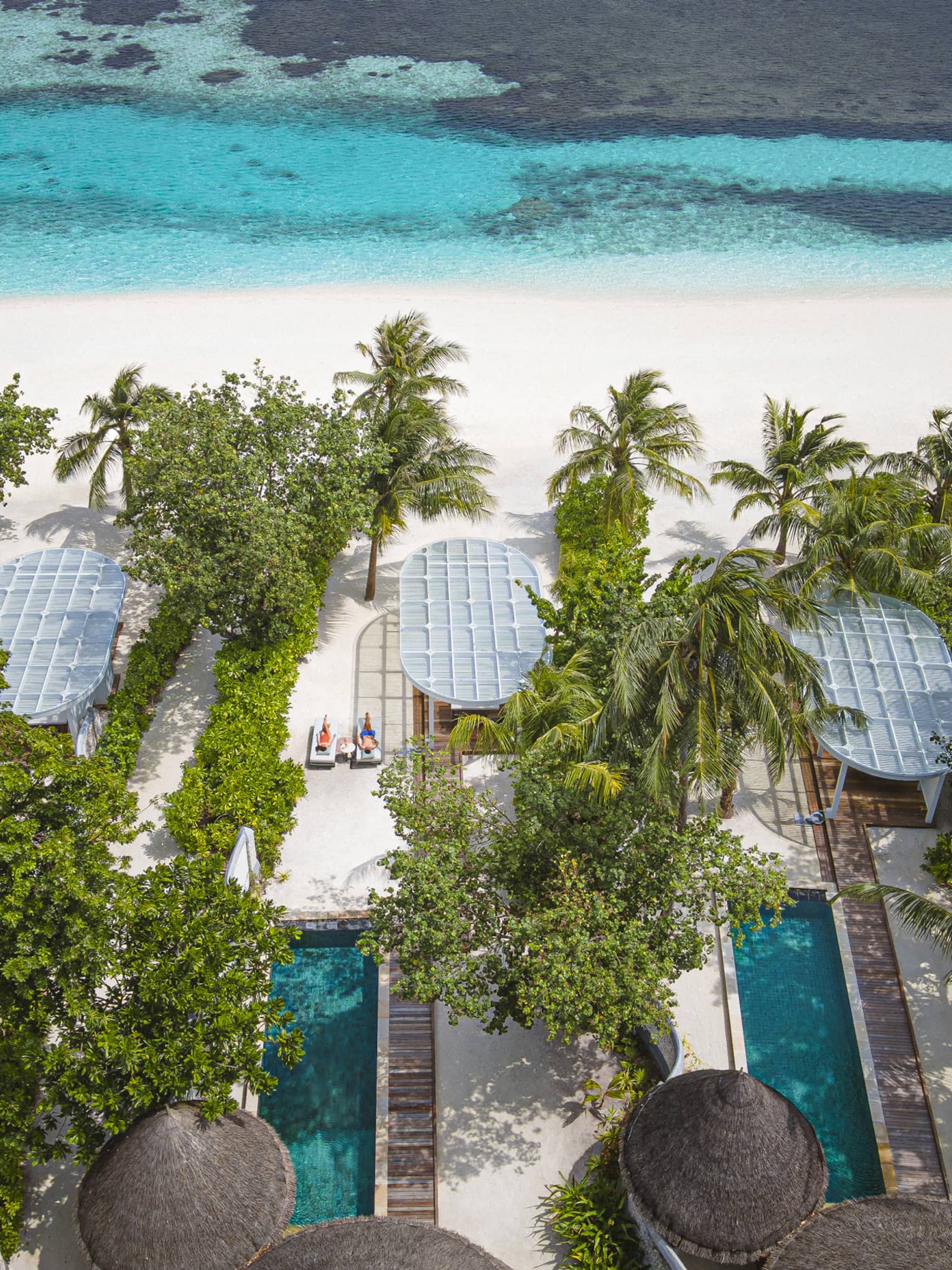 Aerial view of beachfront villas with pools at luxury tropical resort