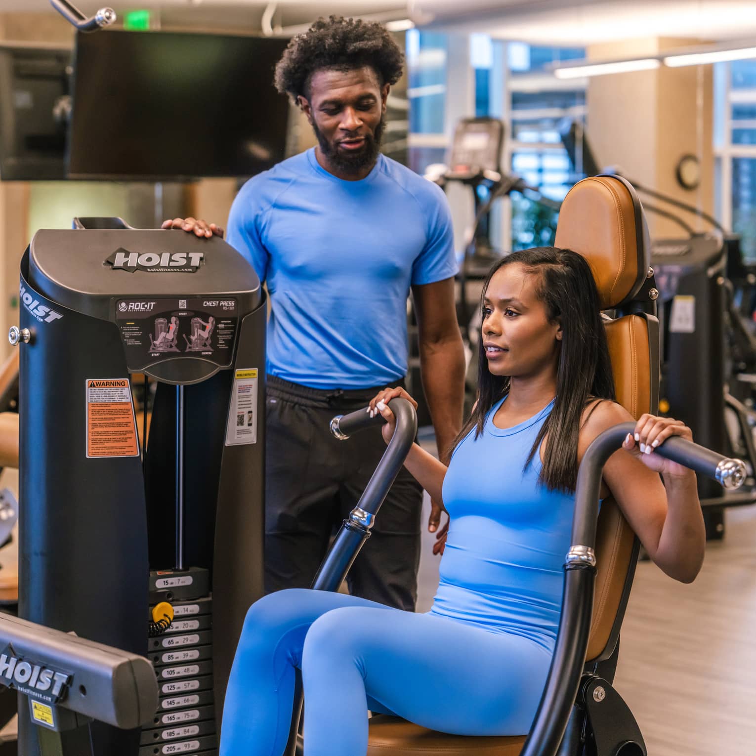 Two guests in a gym, one guest using a gym machine.