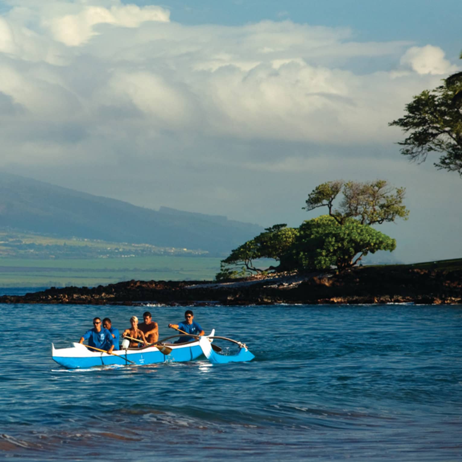 Group of people arrive on shore in an outrigger canoe