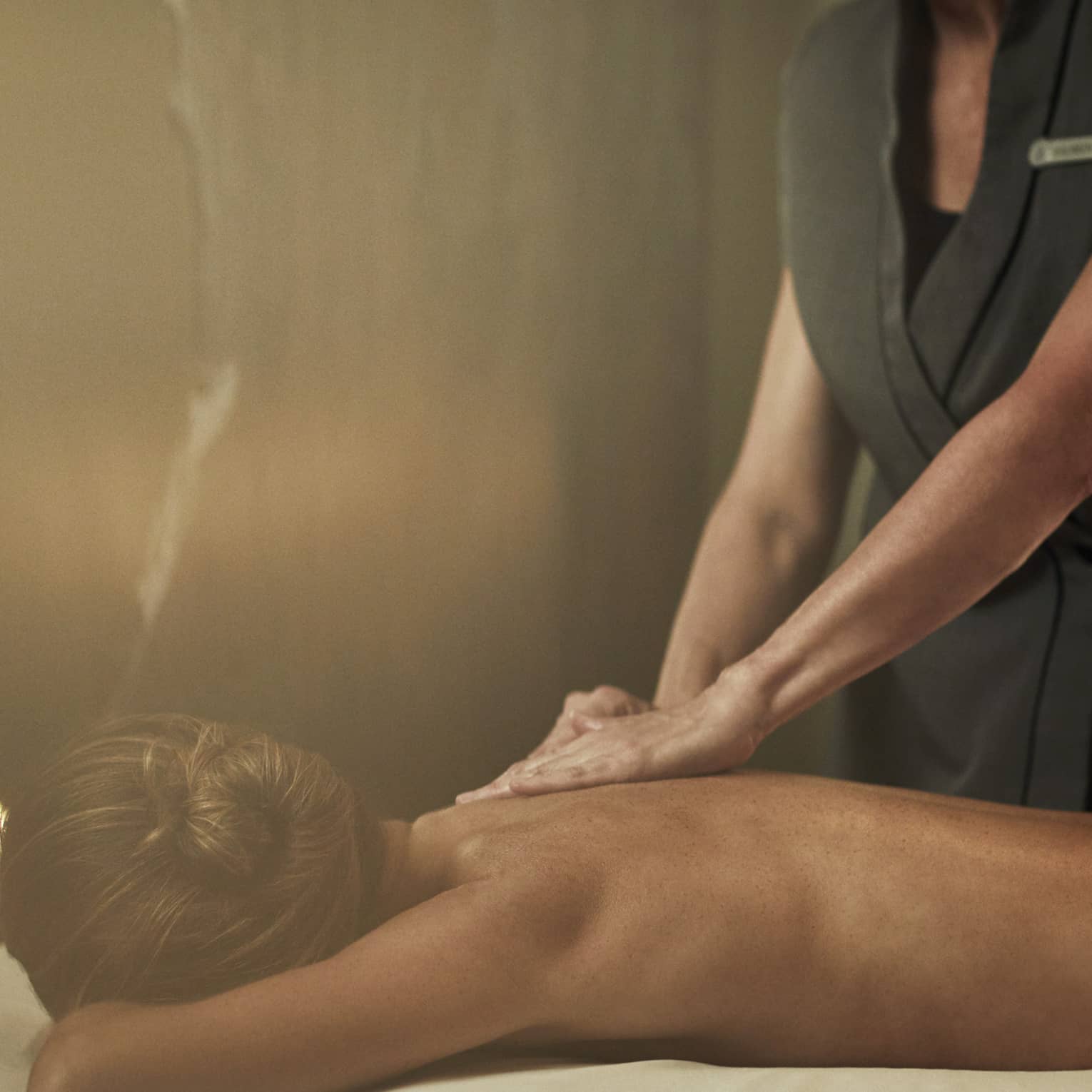A woman laying on a massage bed being given a massage by a staff member.