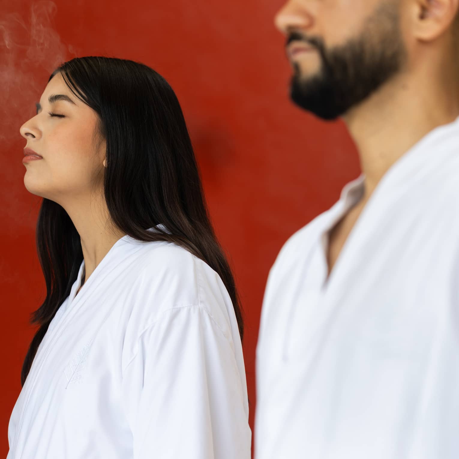 Two people in white spa robes experience  a spa ritual.