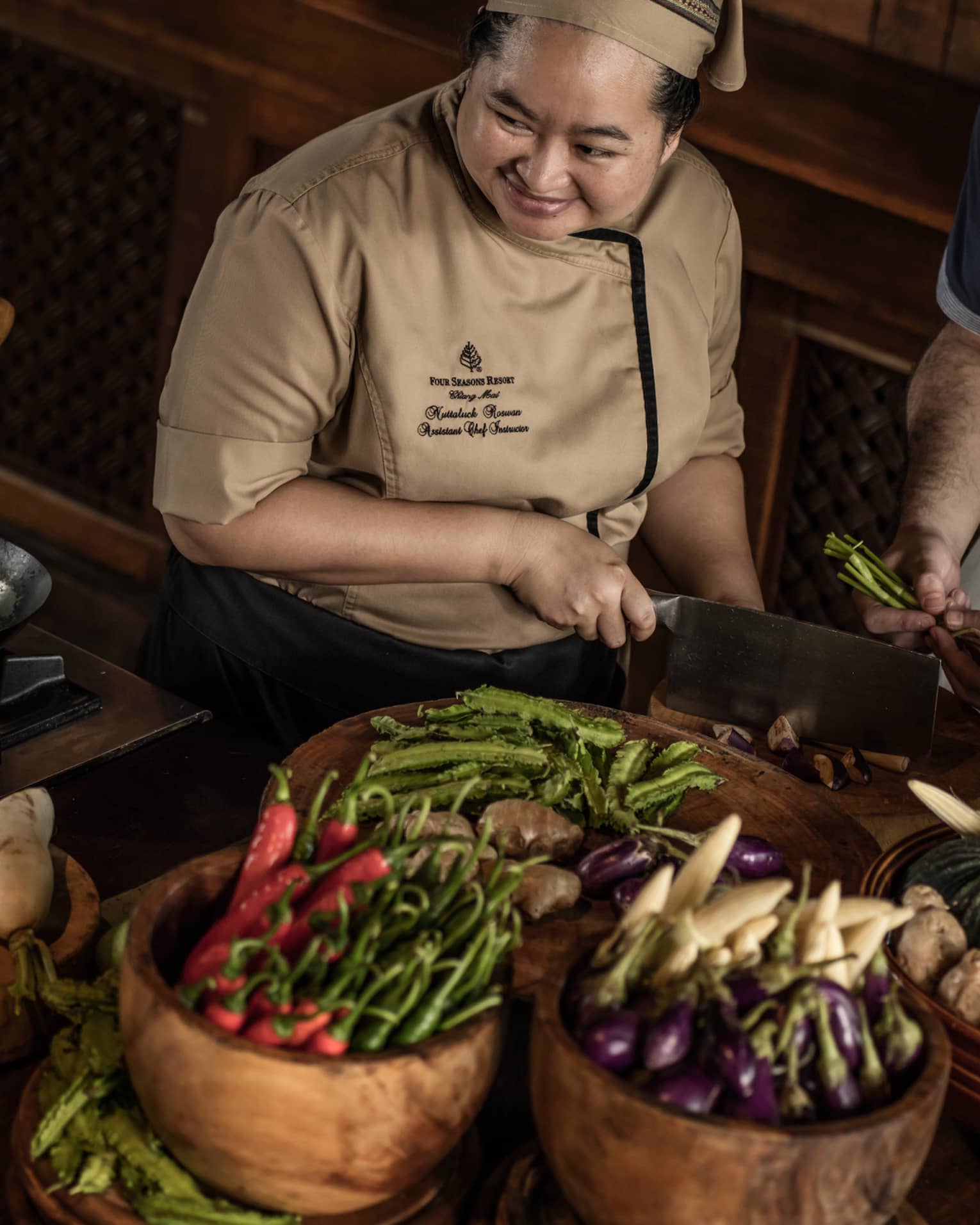  A chef teaching two participants in a cooking class, surrounded by fresh vegetables and ingredients in a rustic kitchen setting.