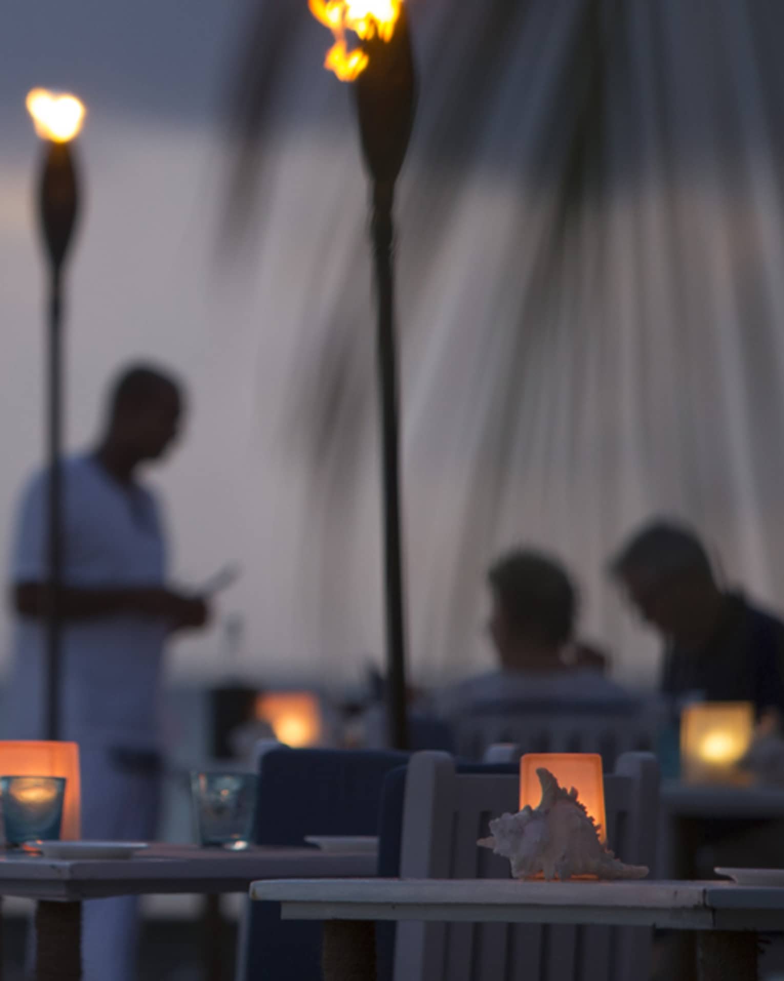 Torch-lit dinner at Baraabaru, silhouettes of couple and server in background
