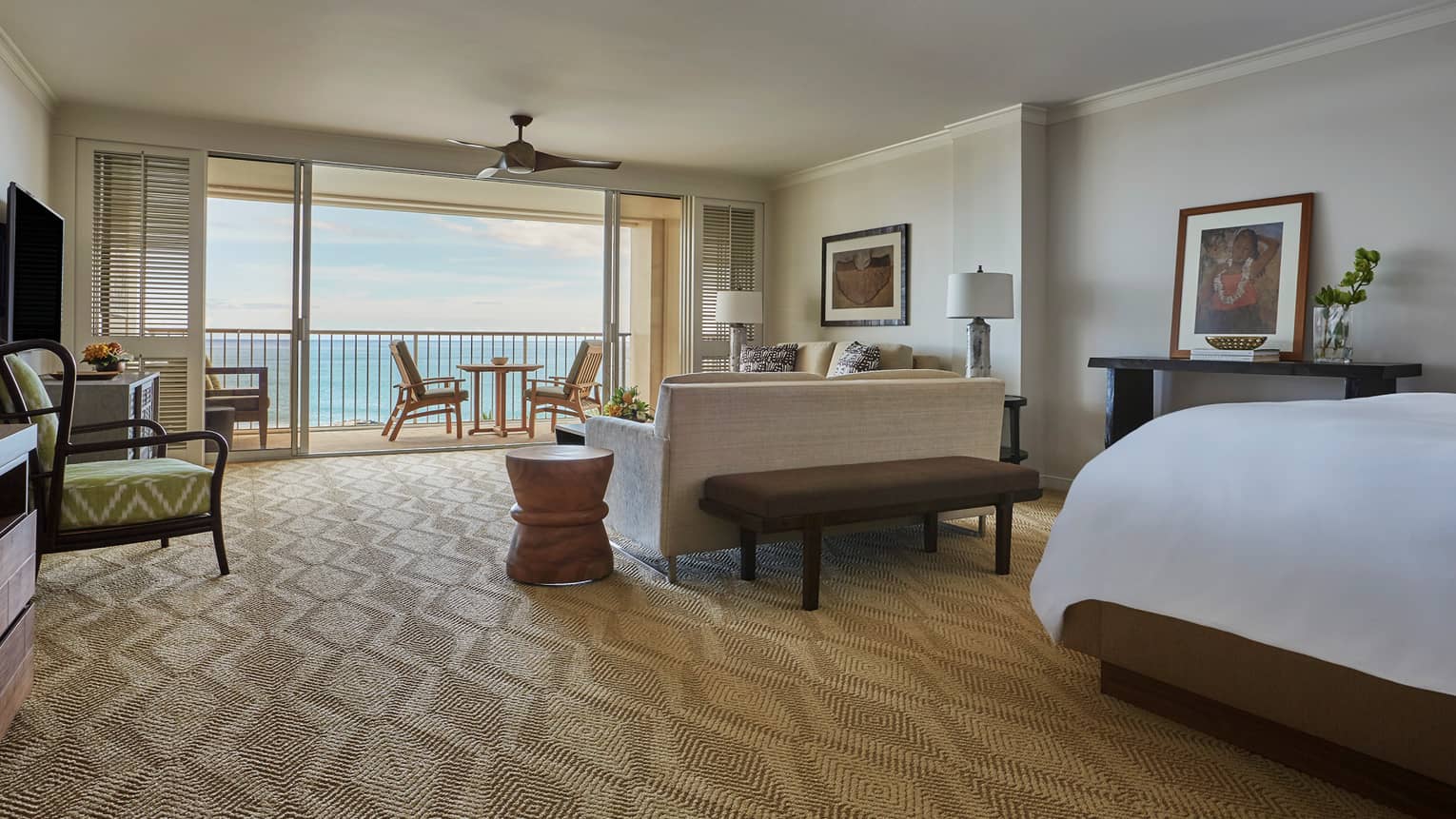 Oceanfront Junior Suite corner of bed behind living room, sofa facing open sliding patio doors