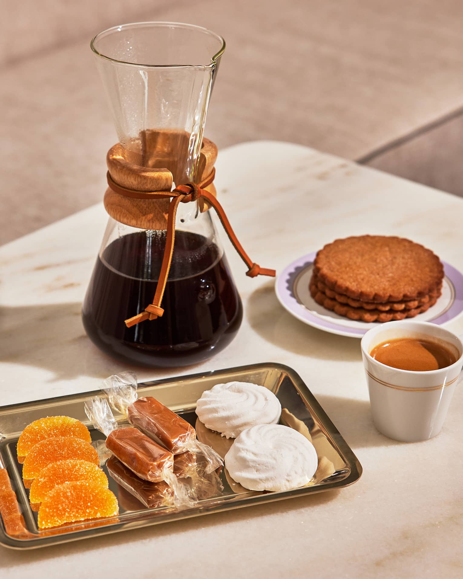 A glass carafe of coffee and plate of sweets, including meringue and Biscoff cookies