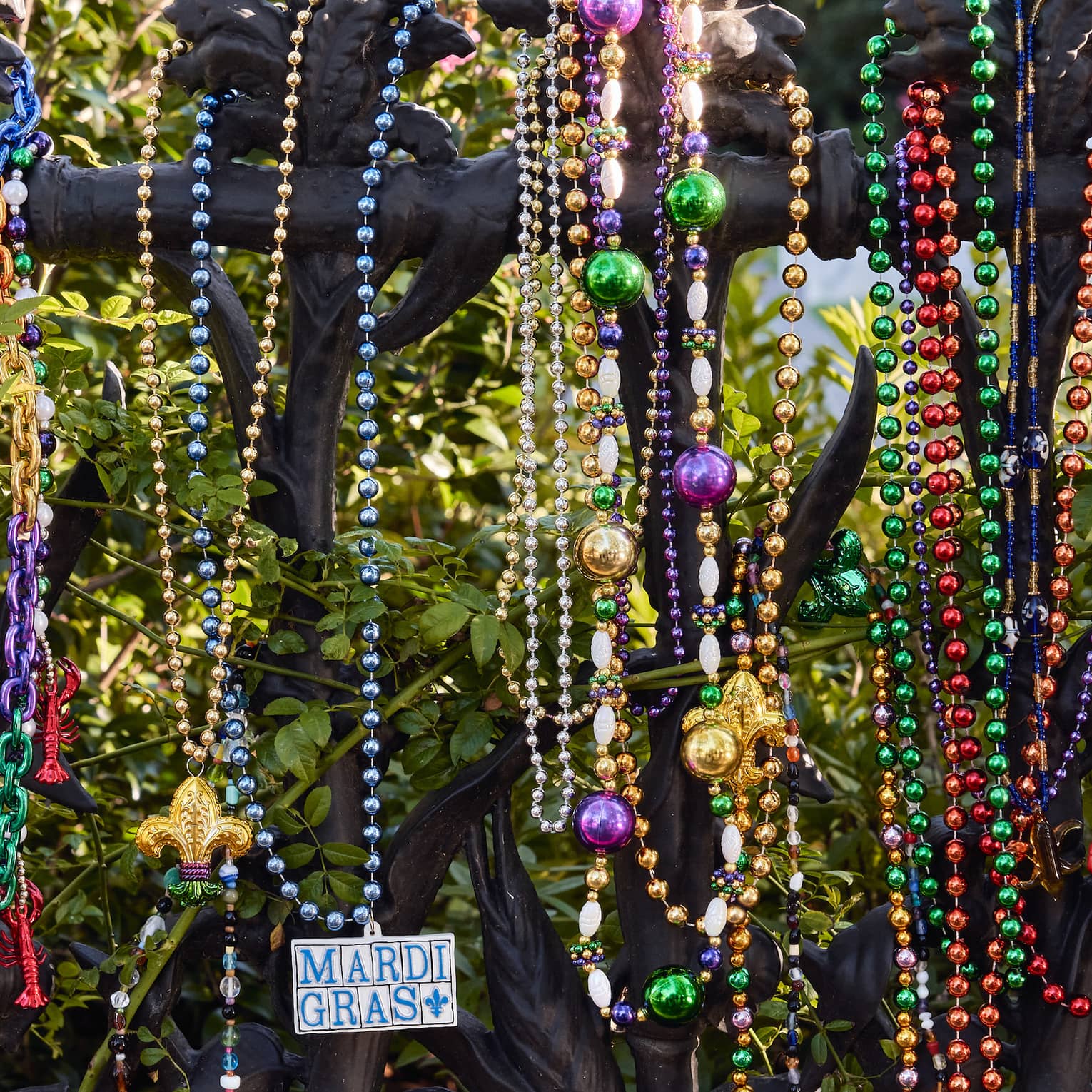 Strands of colourful Mardi Gras beads hanging on a wrought iron post