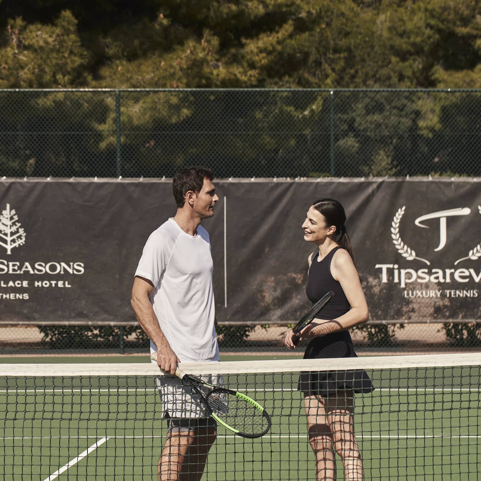A man and woman holding tennis rackets on a court.