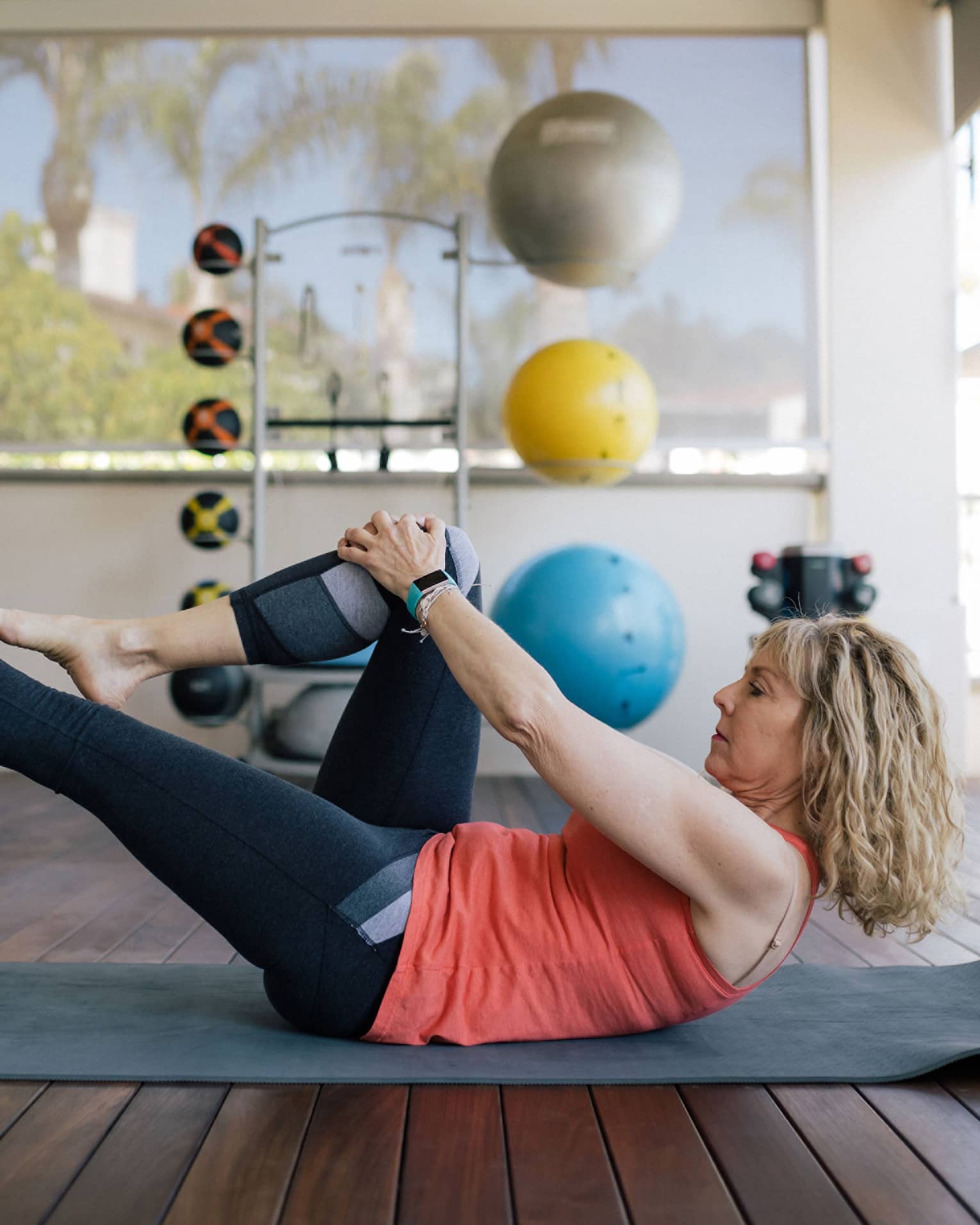 Woman stretches leg on yoga mat in fitness room