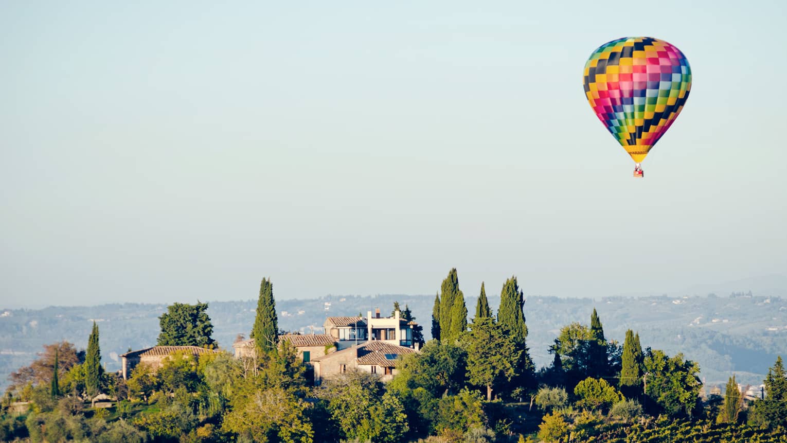 A colorful hot air balloon hovering over a vineyard in Florence
