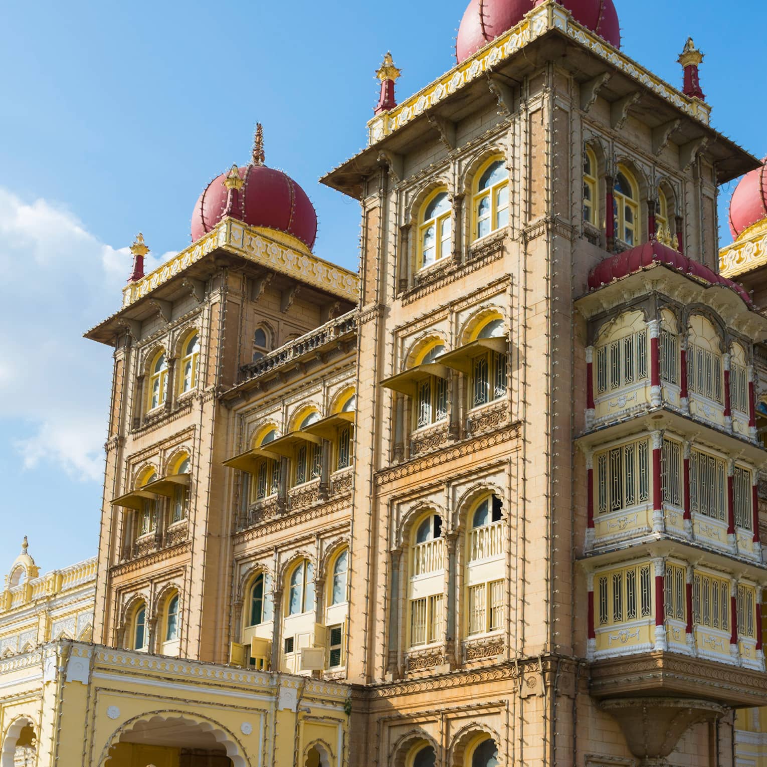 Sprawling palace with arched windows, dome-topped towers and an ornate design, its golden hue contrasted against a sunny sky.