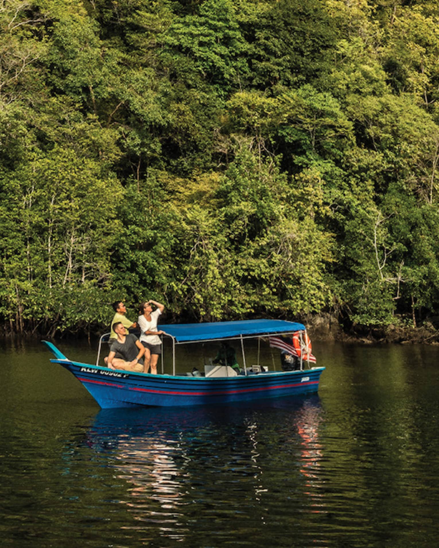 People on small blue boat on river under small rocky mountain