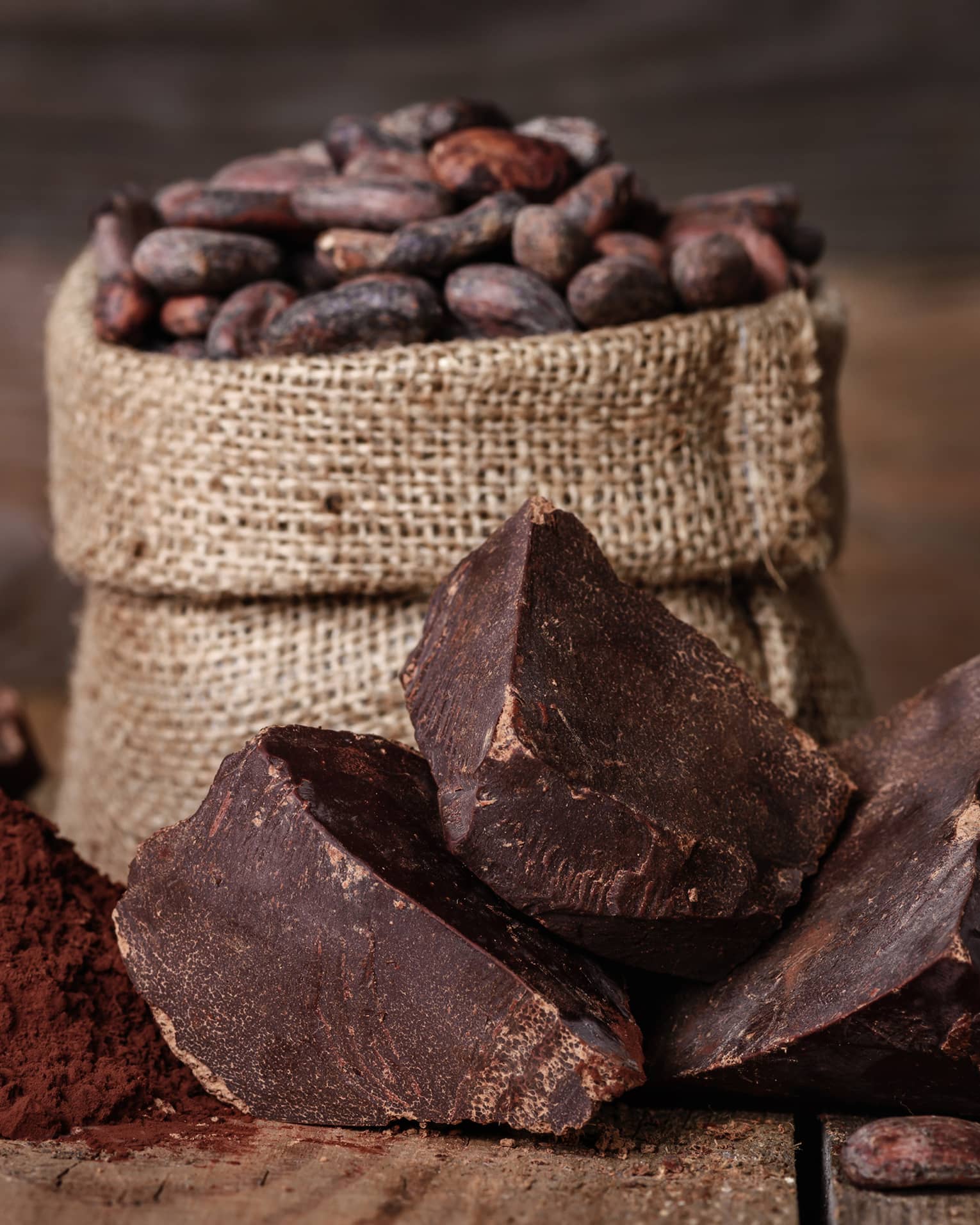 Chunks of chocolate, cocoa powder and coffee beans in a burlap sack