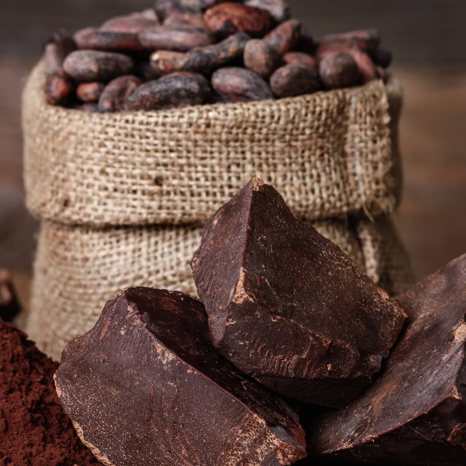 Chunks of chocolate, cocoa powder and coffee beans in a burlap sack