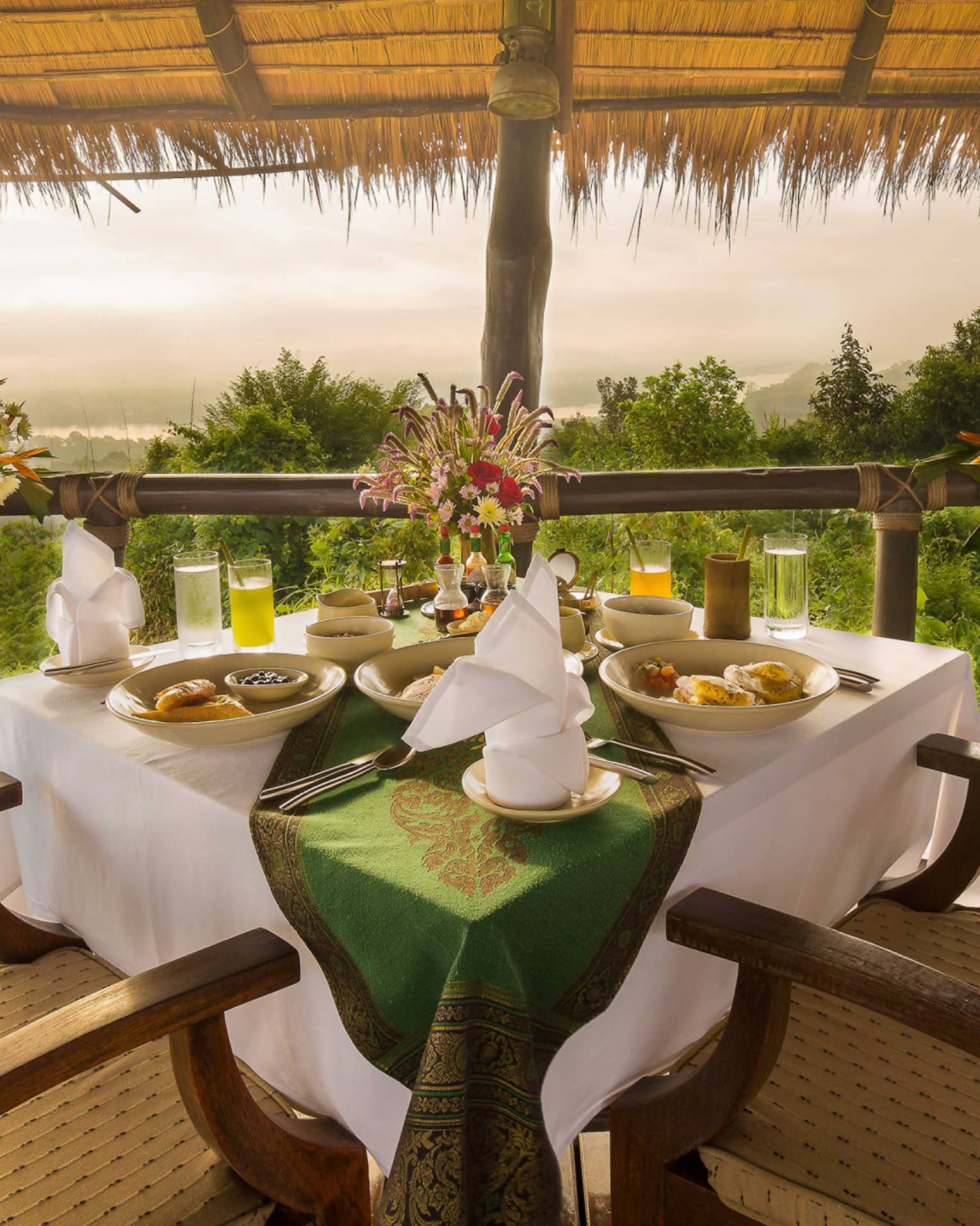 Dining table with two chairs under thatched roof
