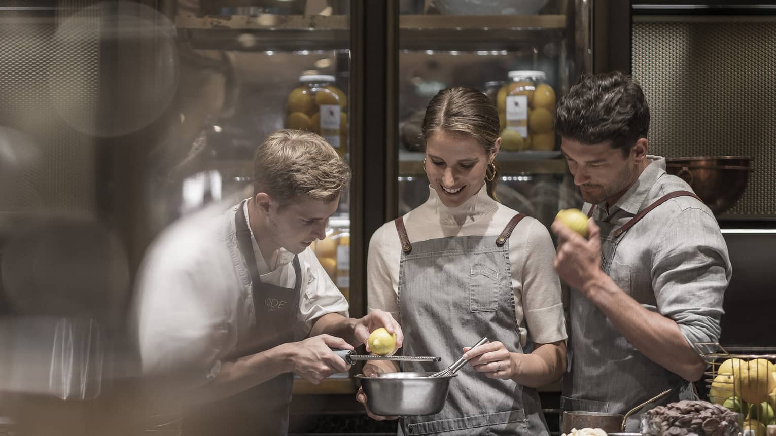 Chef grates lemon over bowl with couple at cooking class demonstration