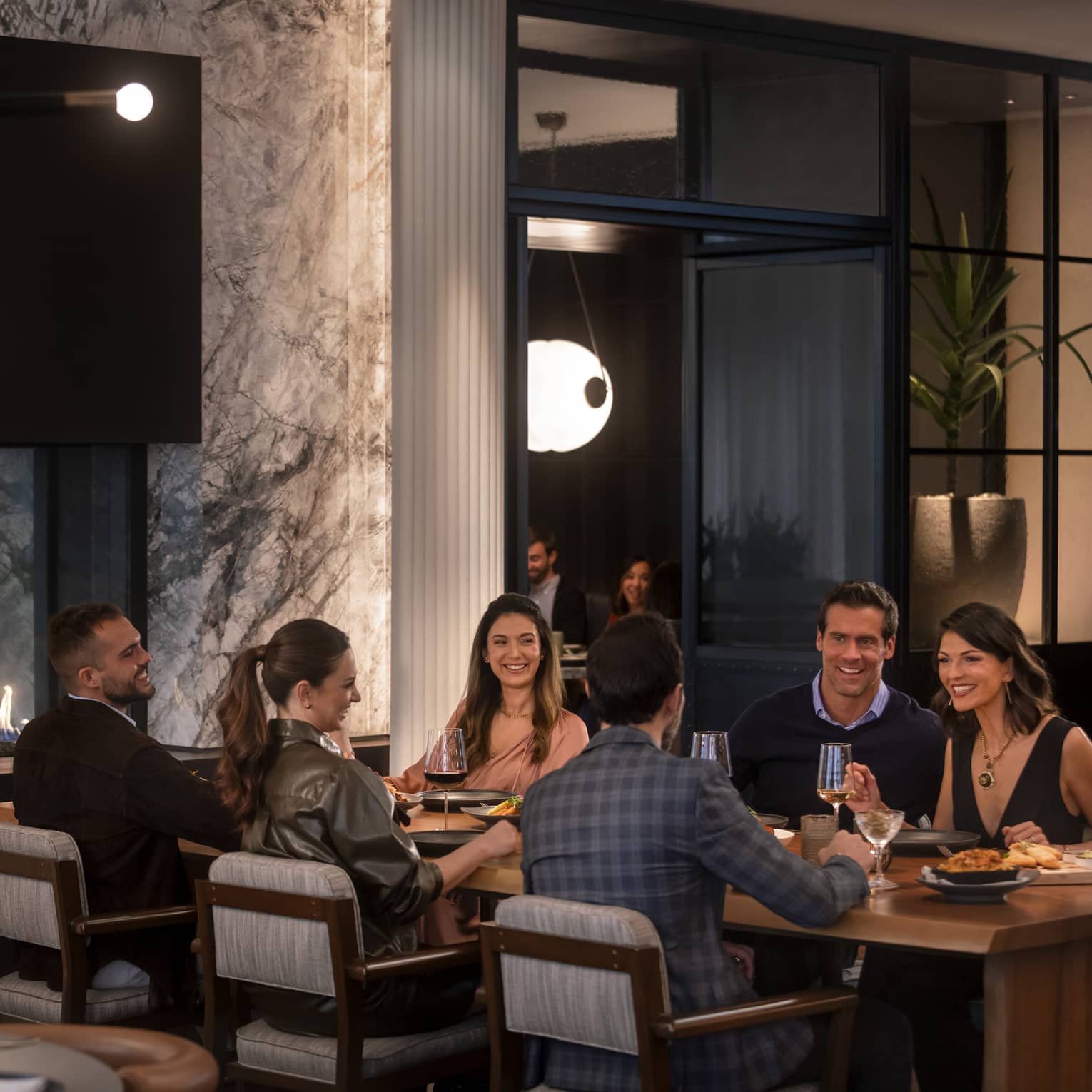 A group of people sitting at a large table in a dimly lit restuarant.