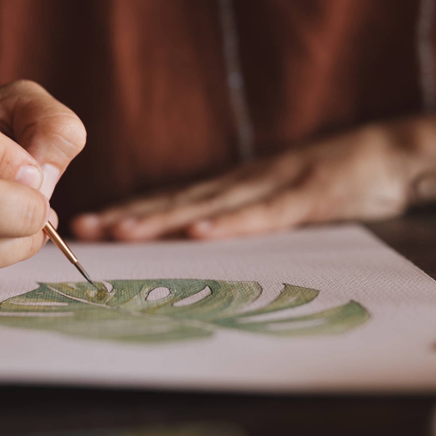 Close-up shot of someone drawing a tropical leaf on thick paper