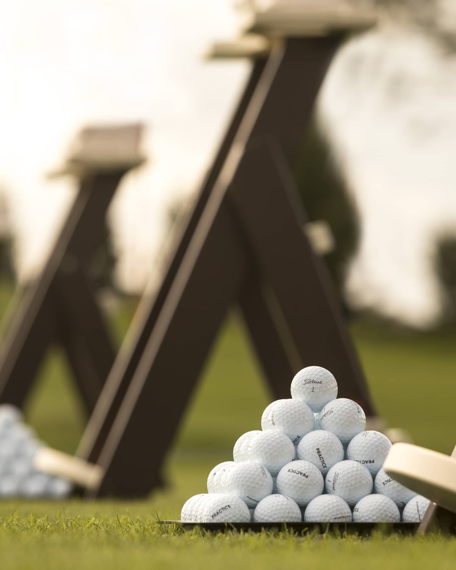 Stacks of white golf balls on lawn in front of wood panels