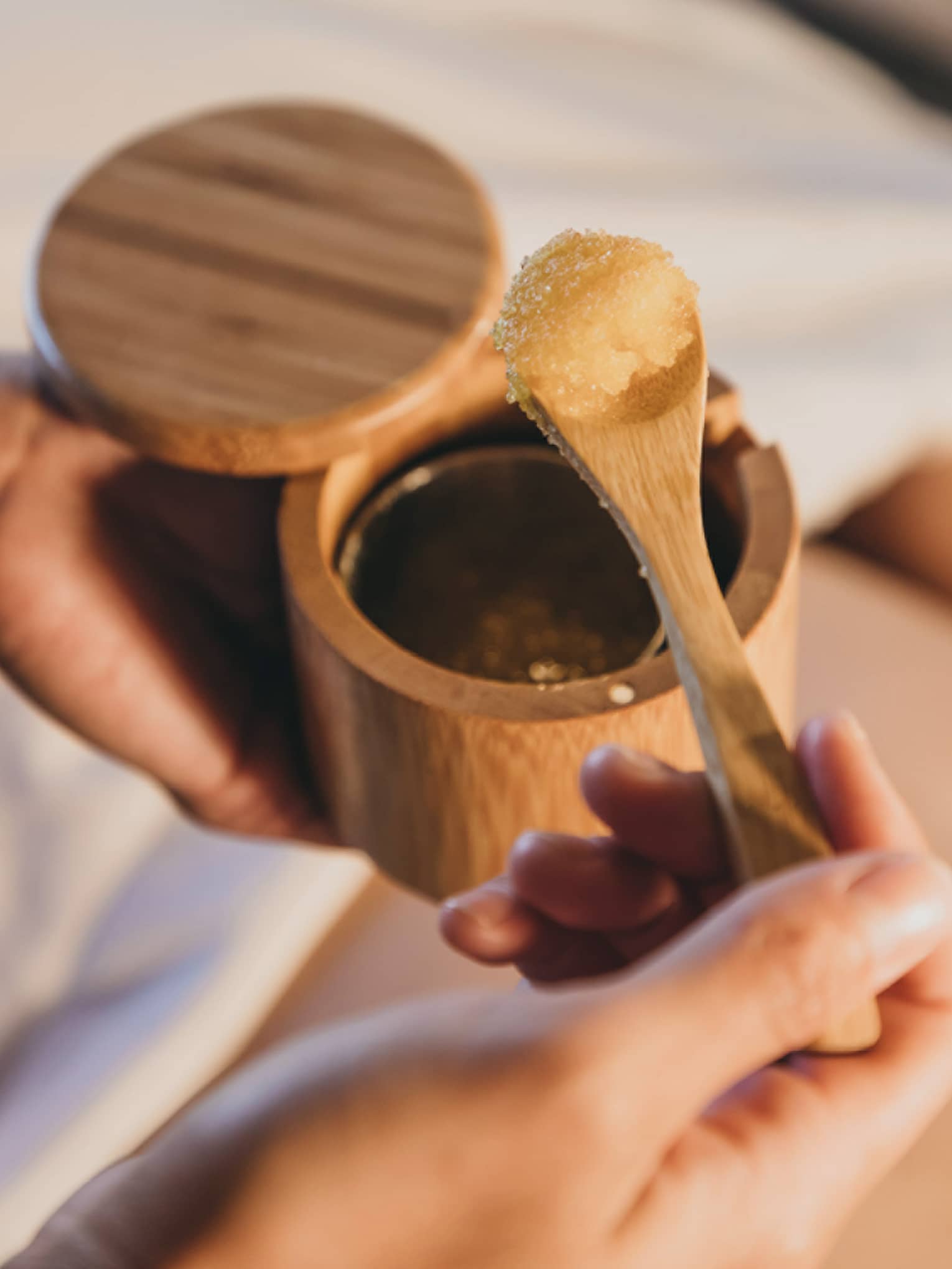 A spa staff member scoops some sugar scrub out of a bamboo container in Hawaii