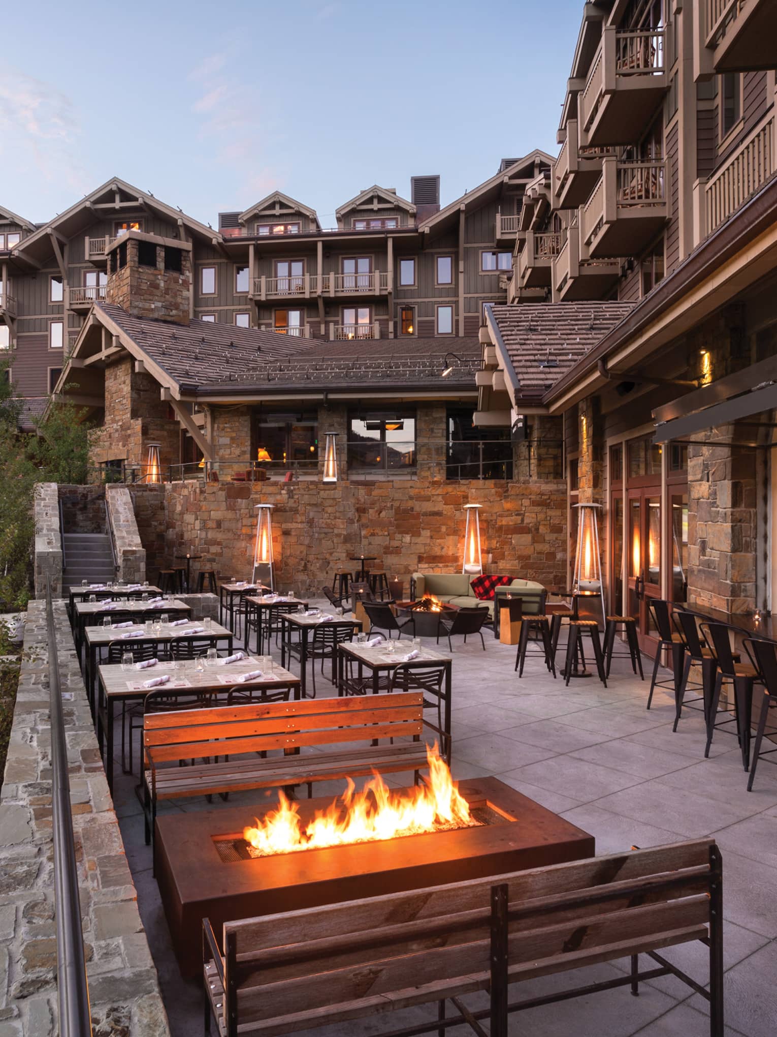 Handle Bar dining patio at dusk, outdoor fireplaces, mountains and lodge in background