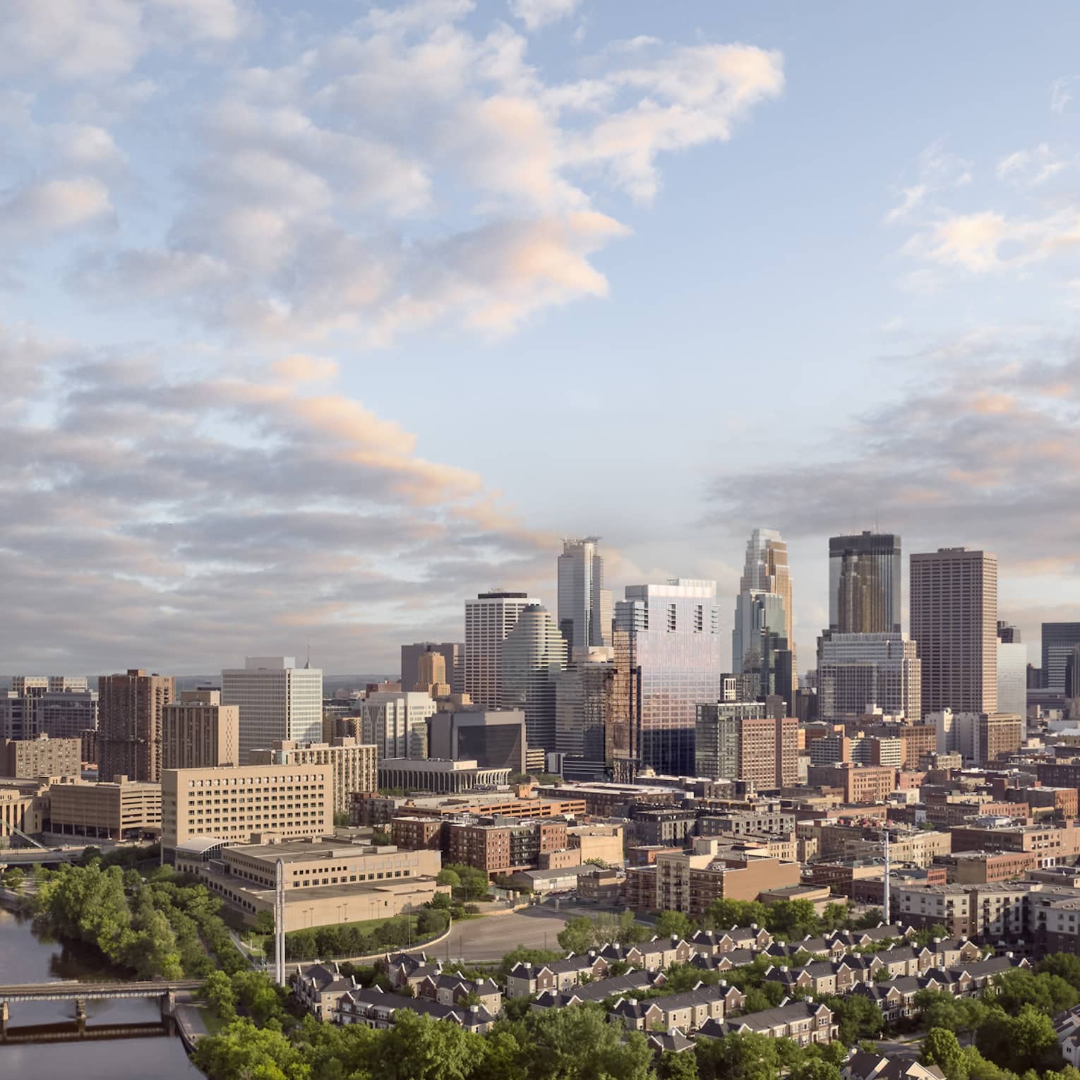 Minneapolis skyline and bridges across Mississippi River, scattered clouds and dense trees