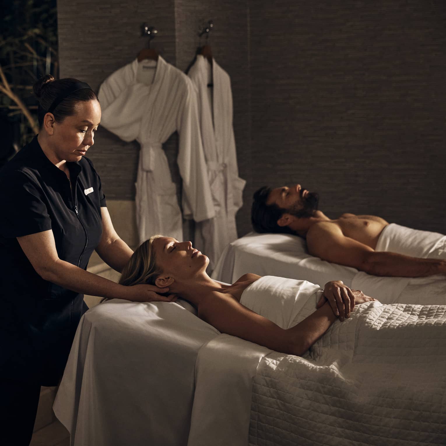 Two guests laying on massage tables in a room with a spa tub.