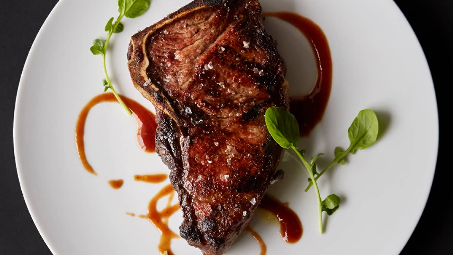 Georgetown Steakhouse Four Seasons Hotel Washington Dc Bourbon Restaurant Grilled Bone In Ribeye Steak Garnished With Brown Sauce Greens On White