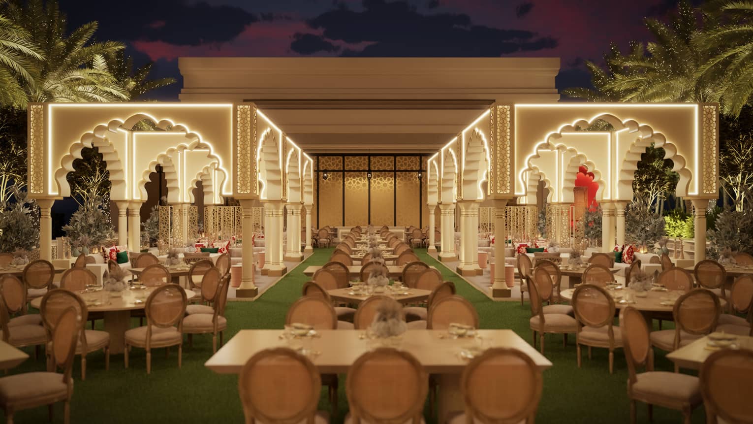 Outdoor lawn area filled with various white-topped tables with two rows of tall Arabesque archways lit up along the edges with palm trees seen along the perimeter, all beneath a night sky
