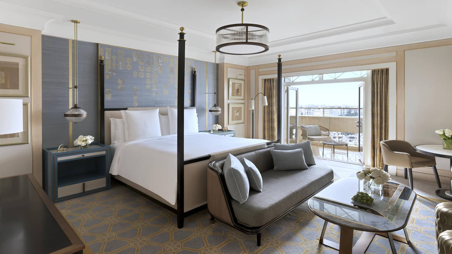 Royal Suite primary bedroom featuring four-post bed, multiple seating areas and doors opening out to a private balcony