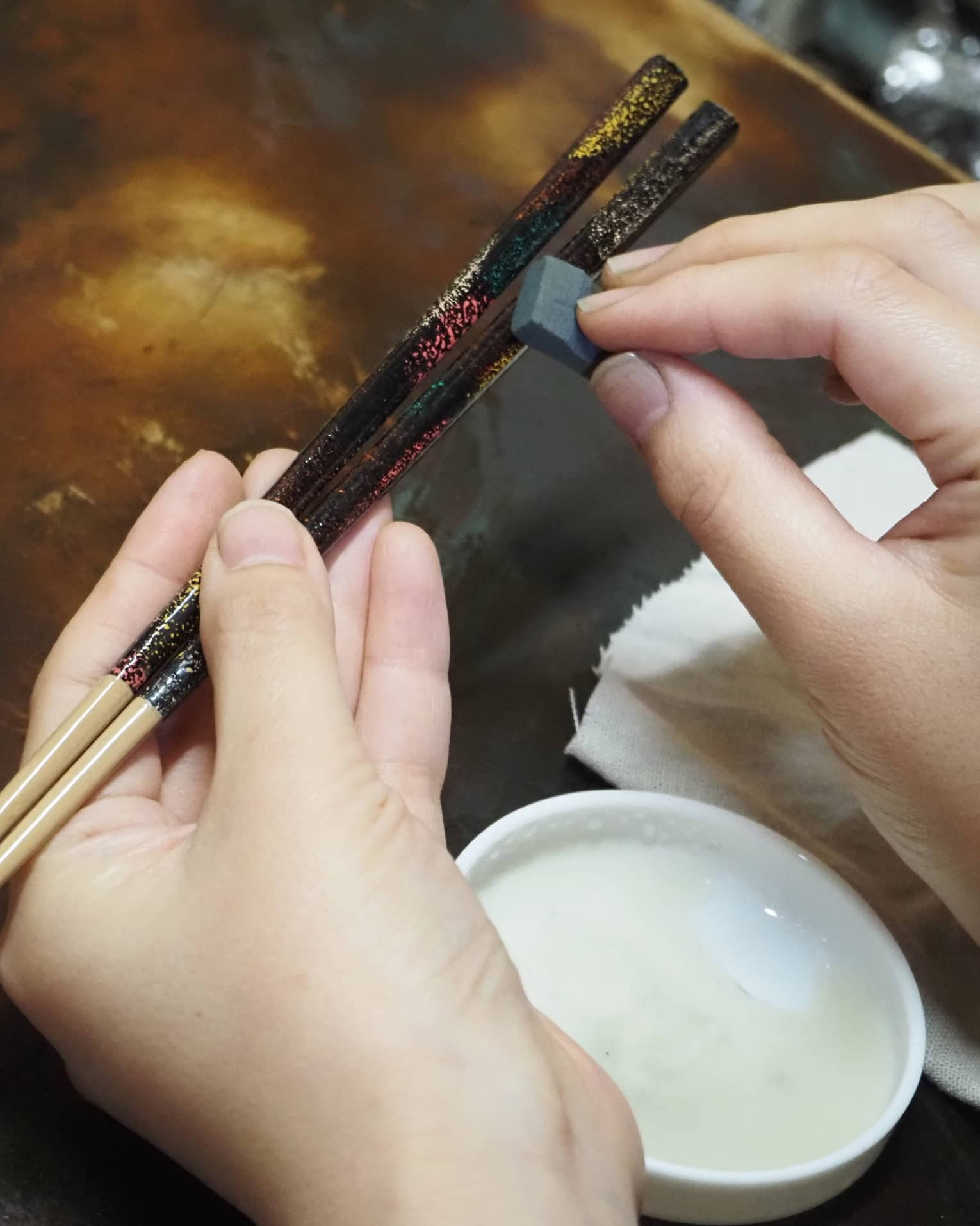 Hands apply Japanese lacquer to customize artisan chop sticks