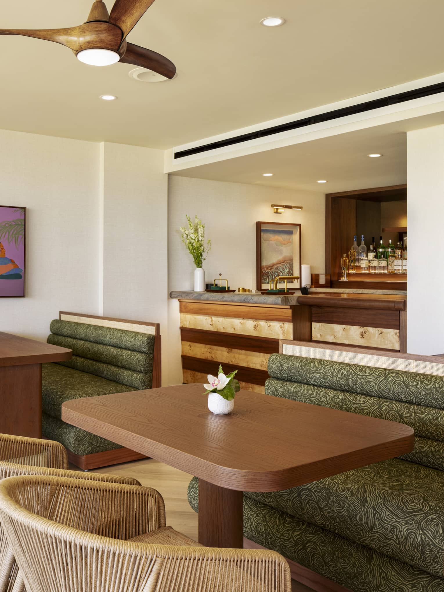 Wooden dining tables in an executive club lounge, featuring large green booths and woven beige chairs