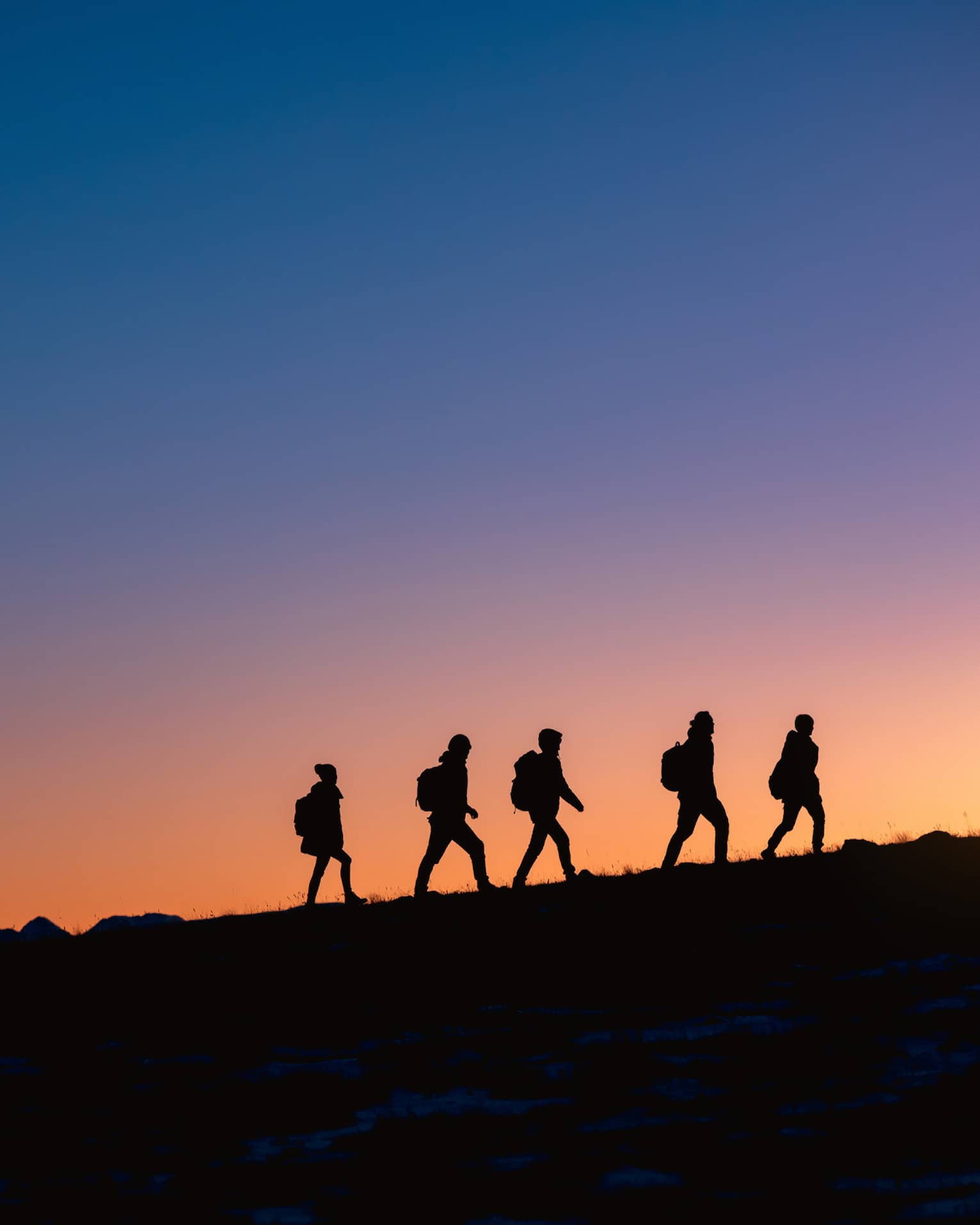 Group hikes on ridge at sunset