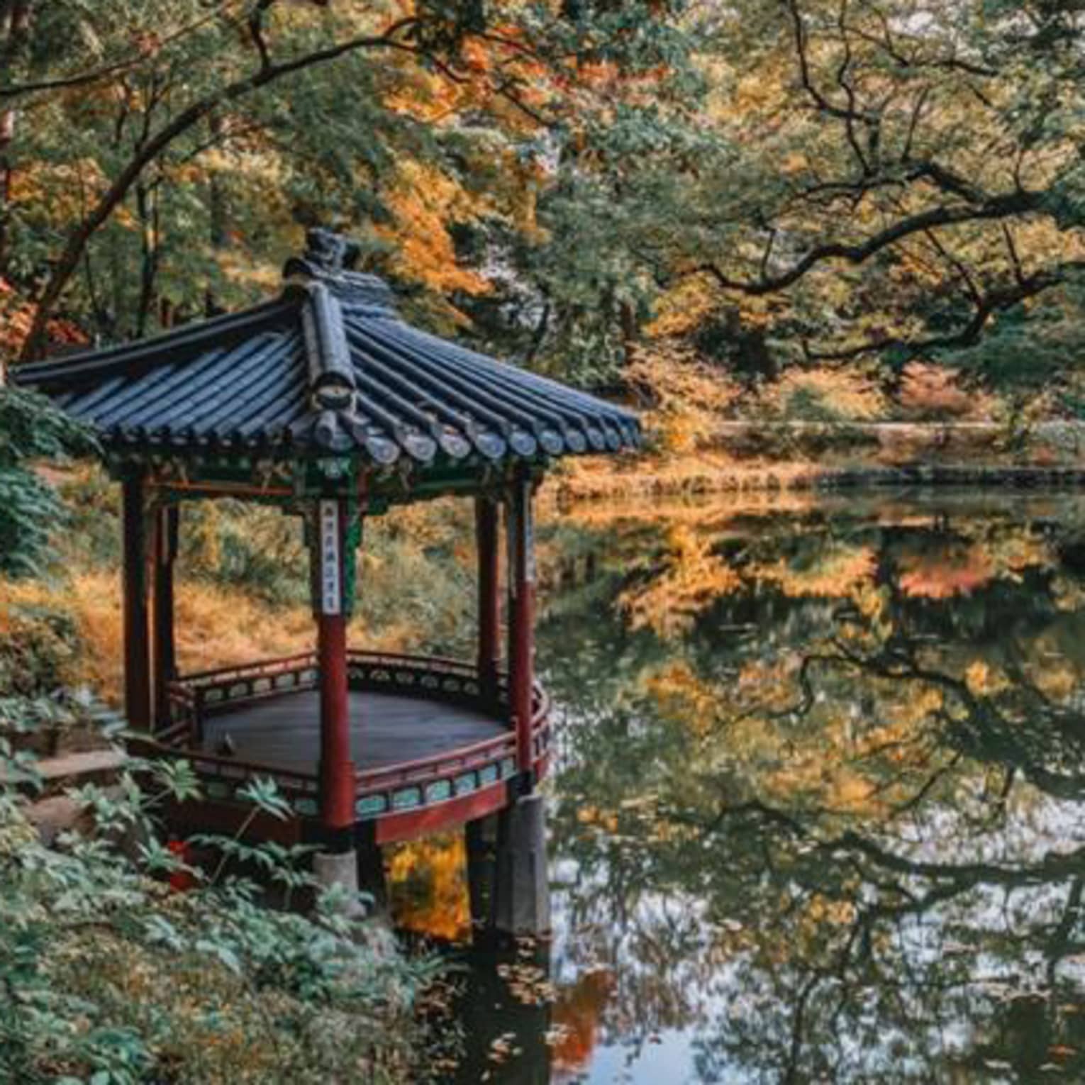 Small overwater gazebo at lake surrounded by autumn foliage