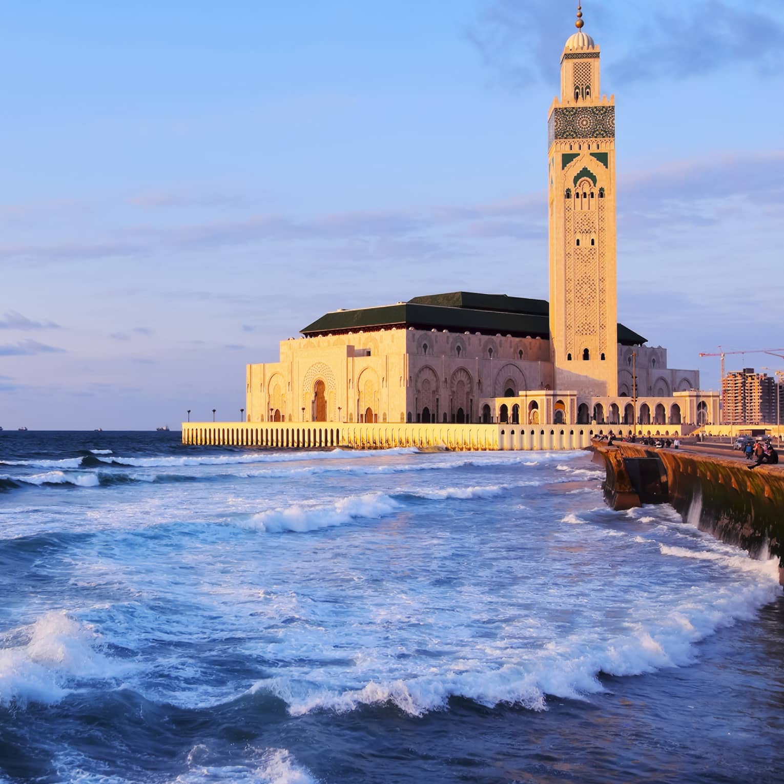 Aside rolling waves stands a golden mosque with domed archways carved into all sides and a towering minaret with a domed top.