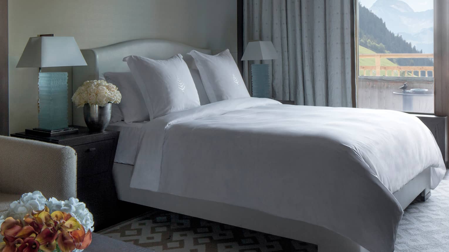 Deluxe One-Bedroom Suite bed with white linens by large window