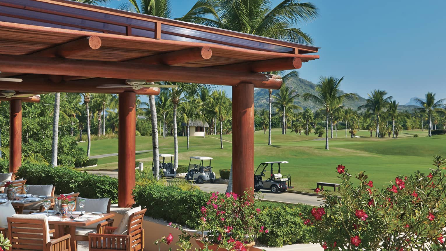 Tail of the Whale patio dining lounge under large wood awning, next to path with white golf carts