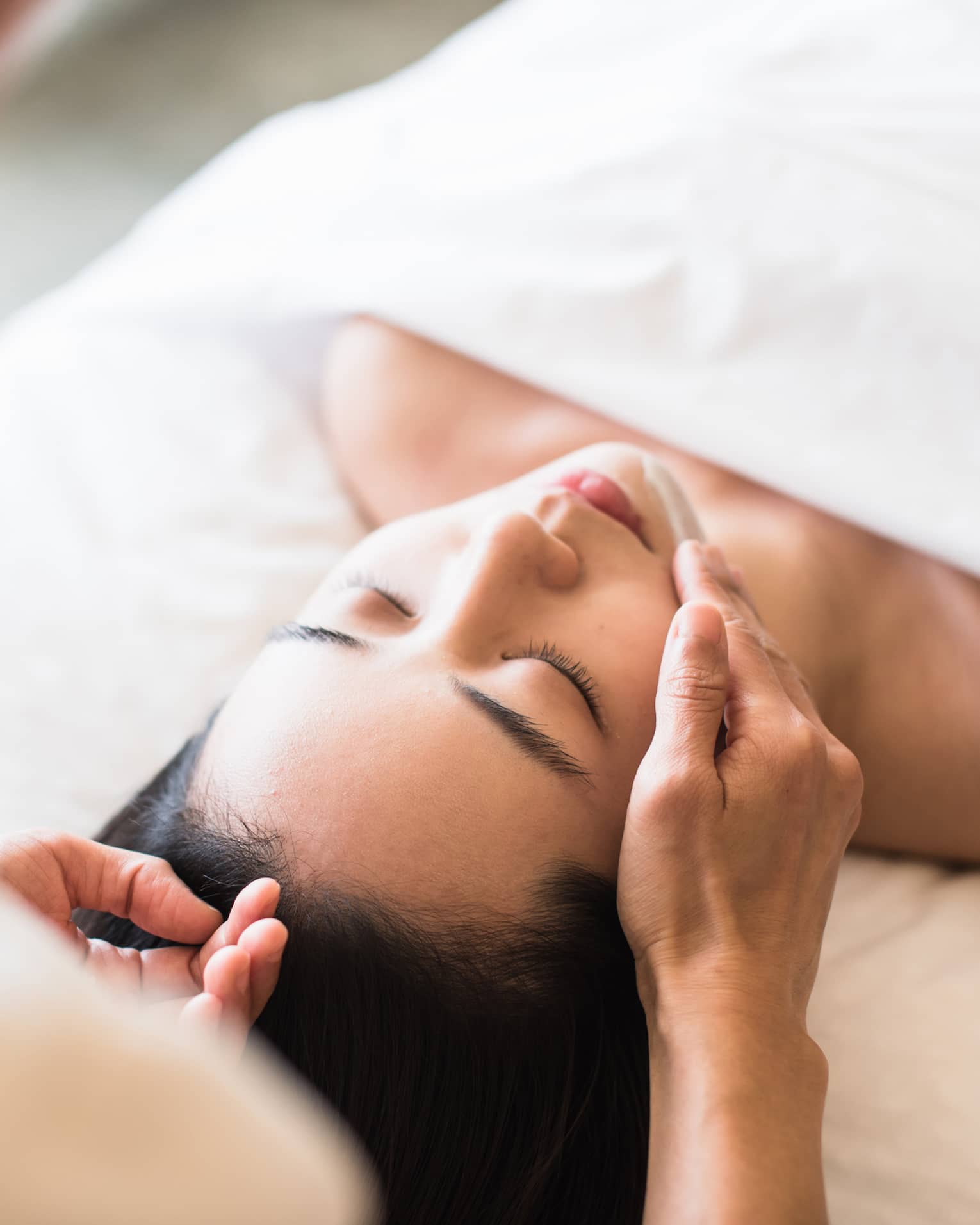A guest receiving a soothing facial at a spa, lying on a massage table, surrounded by calming décor and soft lighting.