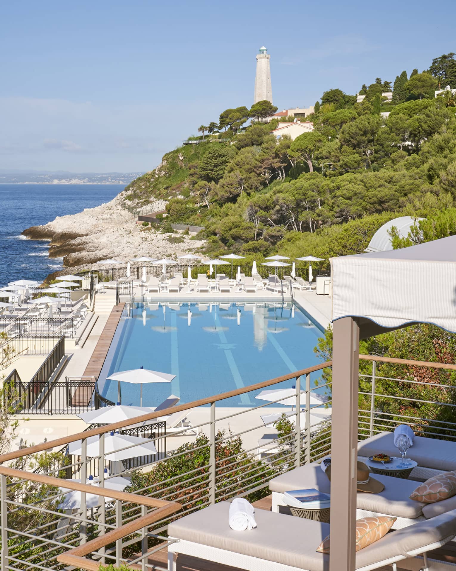 View from terrace of Club Dauphin pool, Mediterranean, green hillside and lighthouse