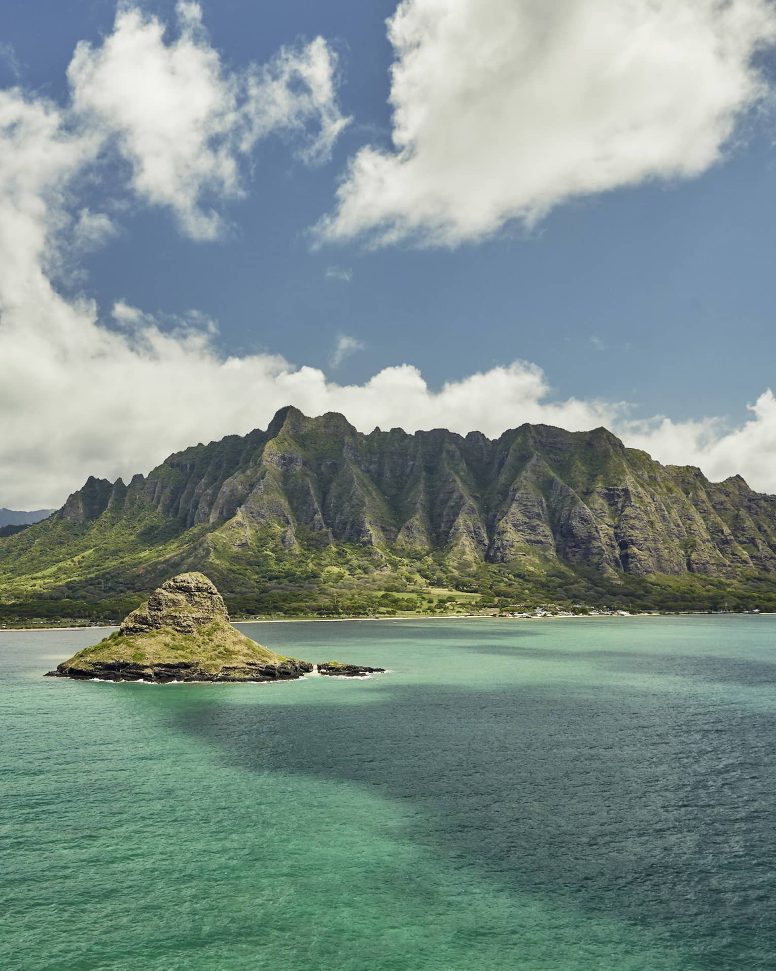 Sweeping green Oahu, Hawaii mountains, small island over turquoise lagoon, white clouds