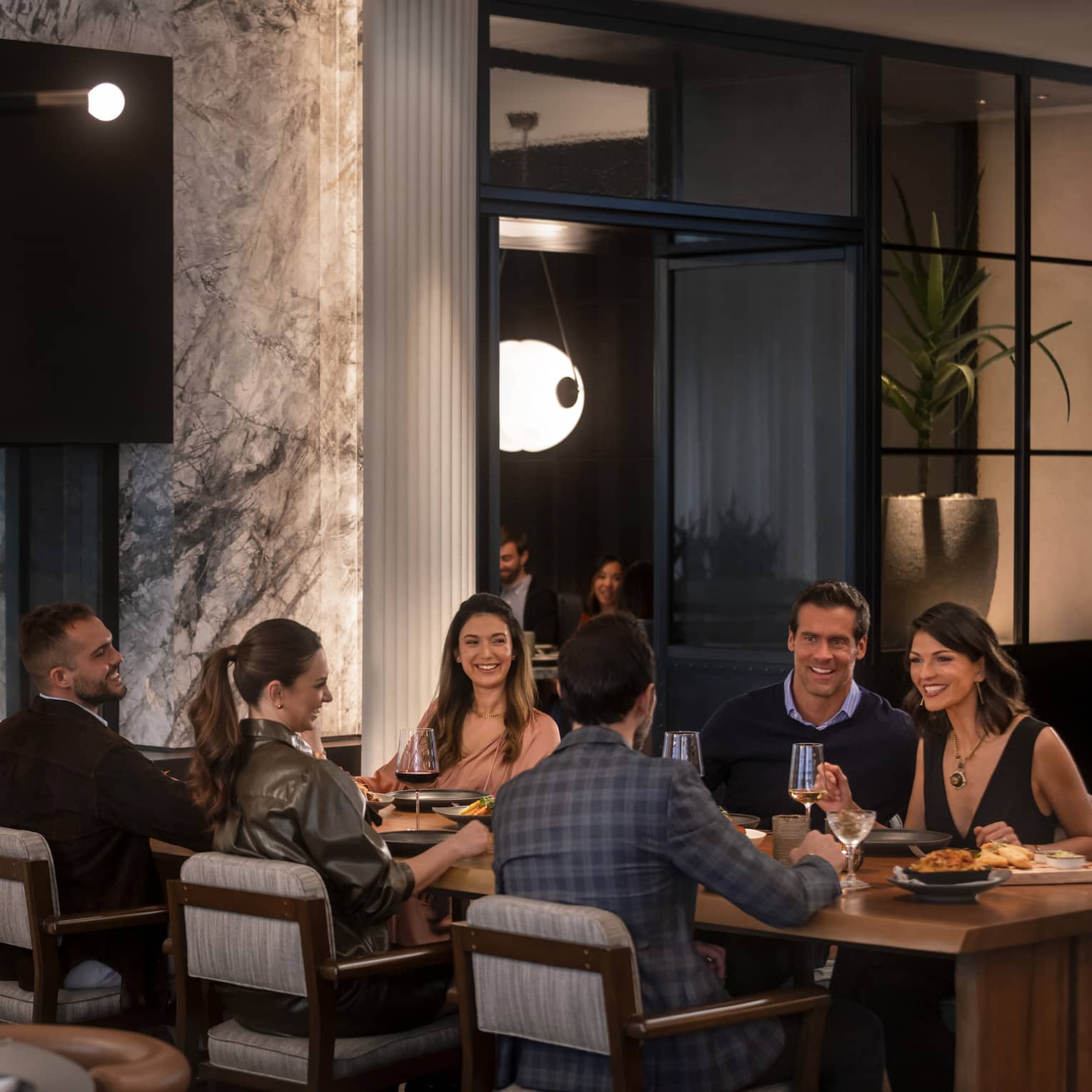 A group of people sitting at a large table in a dimly lit restuarant.