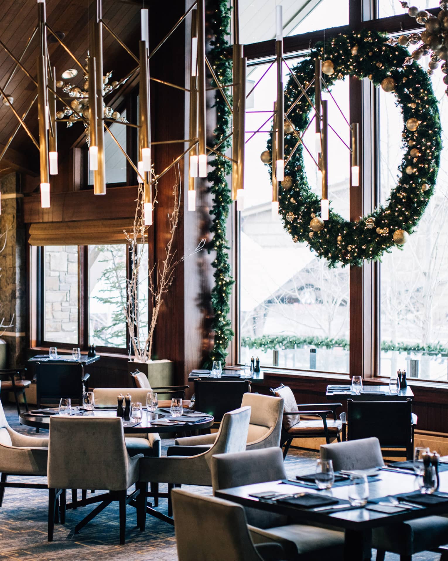 The inside of a restaurant with holiday decorations and snow visible through a large window.