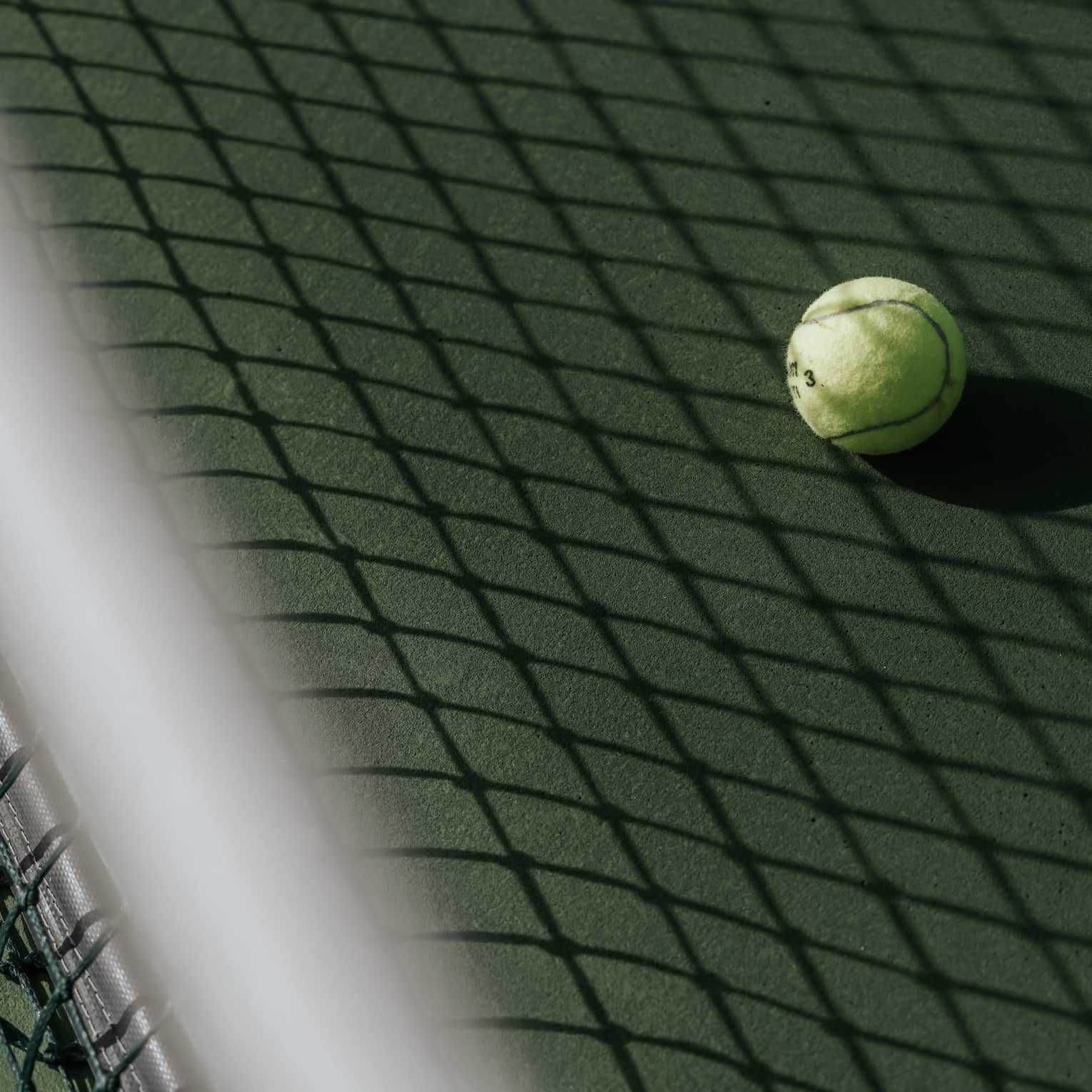 Tennis ball on tennis court with shadow of net