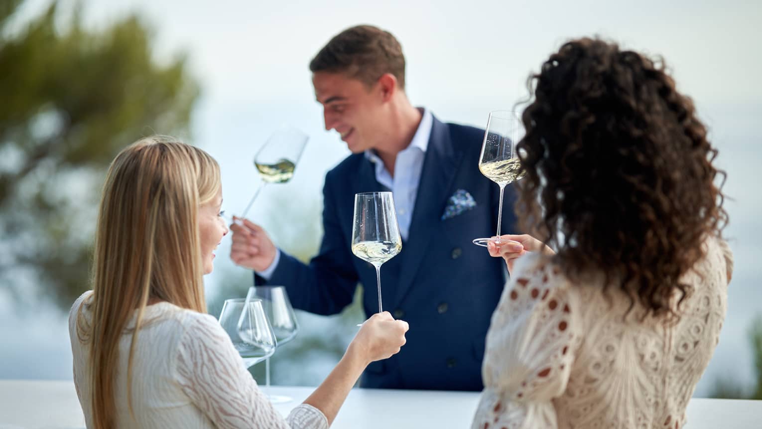 Head Sommelier Alessandro Nigro Imperiale sniffing glass of white wine with two female guests doing the same