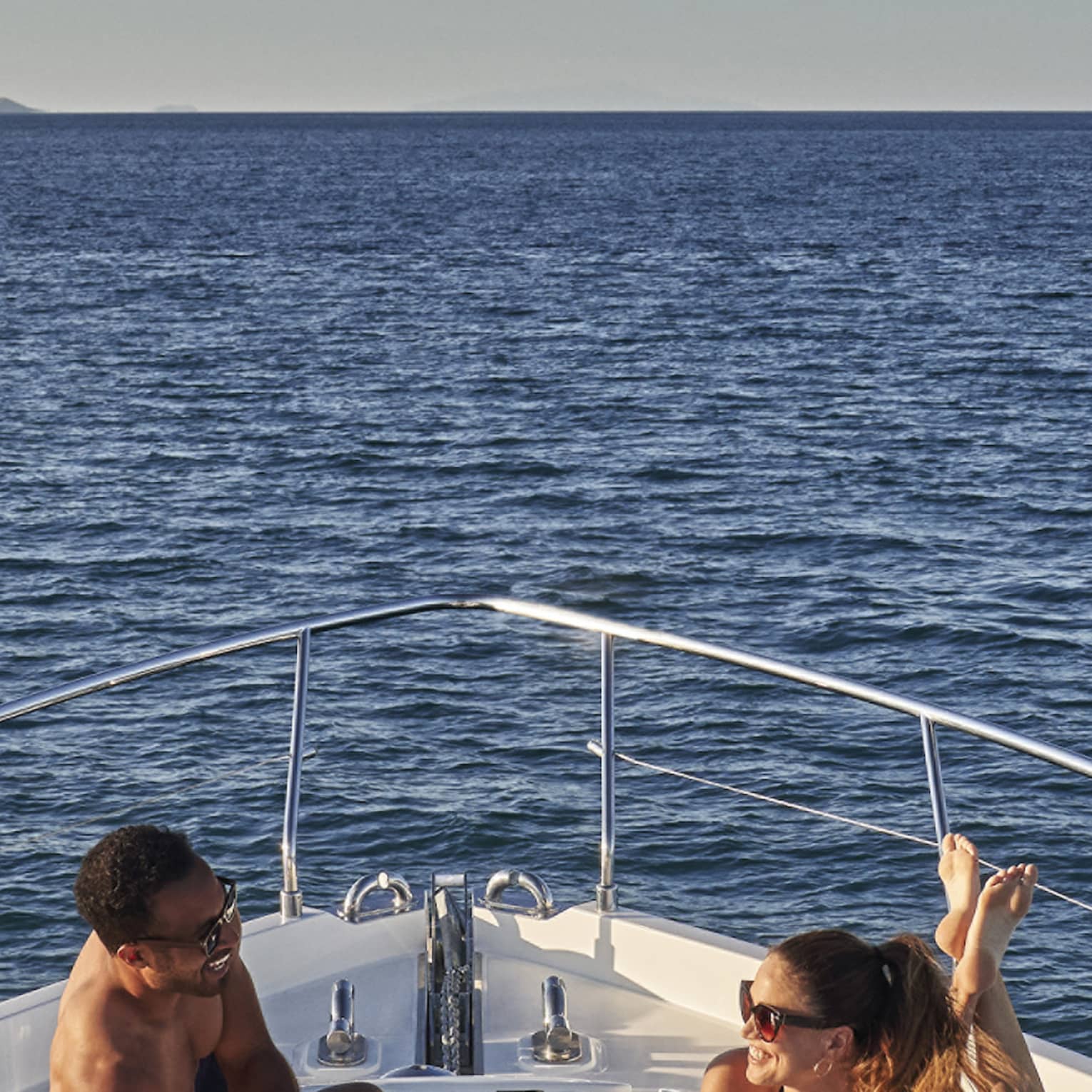 Man and woman lay on front of yacht