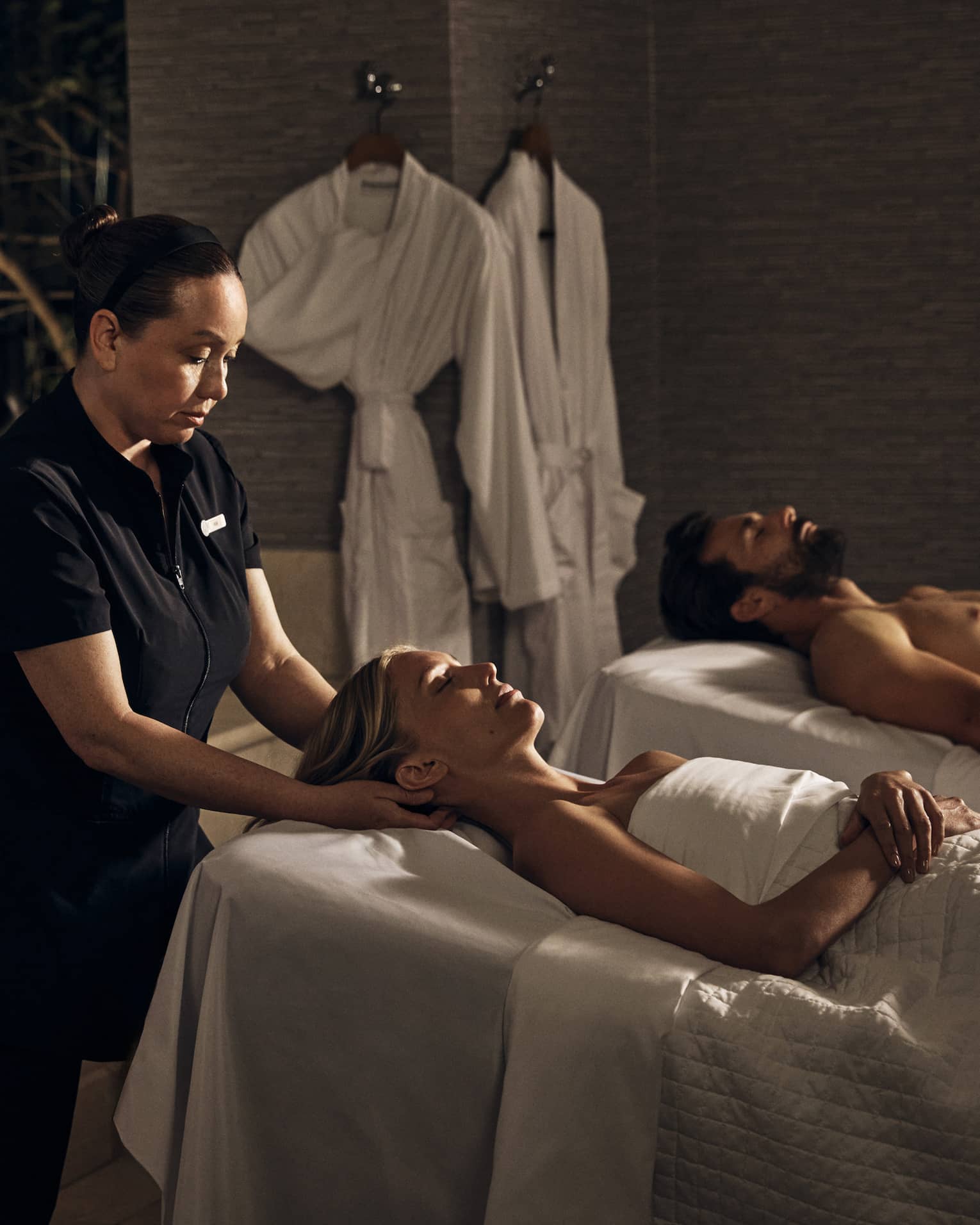 Two guests laying on massage tables in a room with a spa tub.